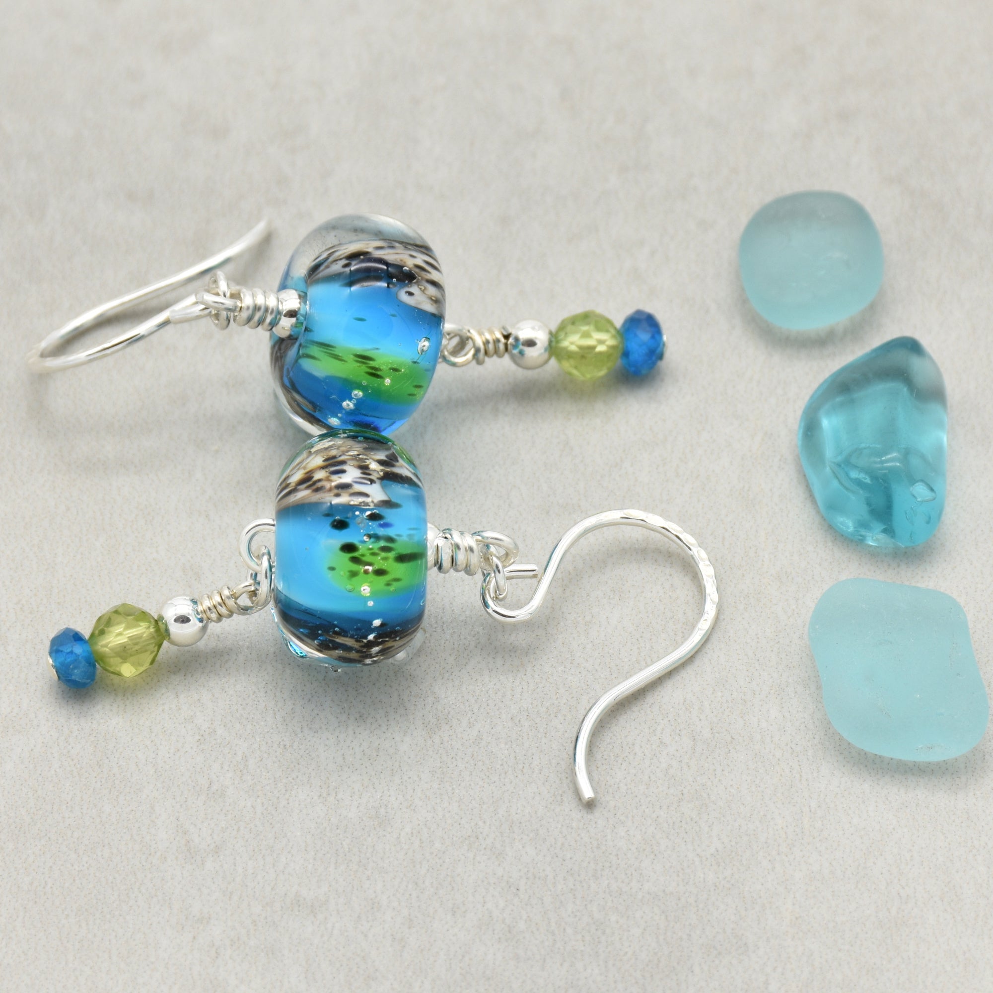 Colorful artisan lampwork glass earrings with sterling silver ear wires, peridot and apatite on a light surface - handmade with love by Ruby Acorn