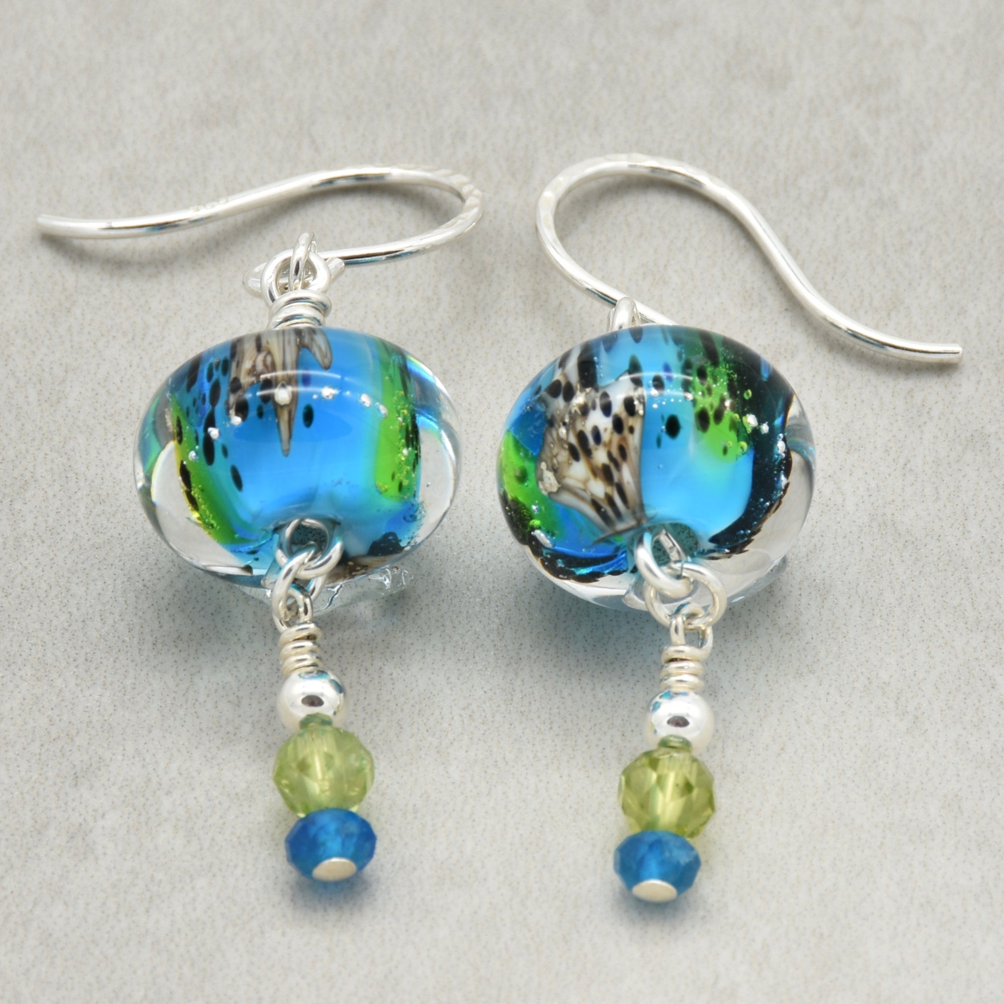 Colorful artisan lampwork glass earrings with sterling silver ear wires, peridot and apatite on a light surface - handmade with love by Ruby Acorn
