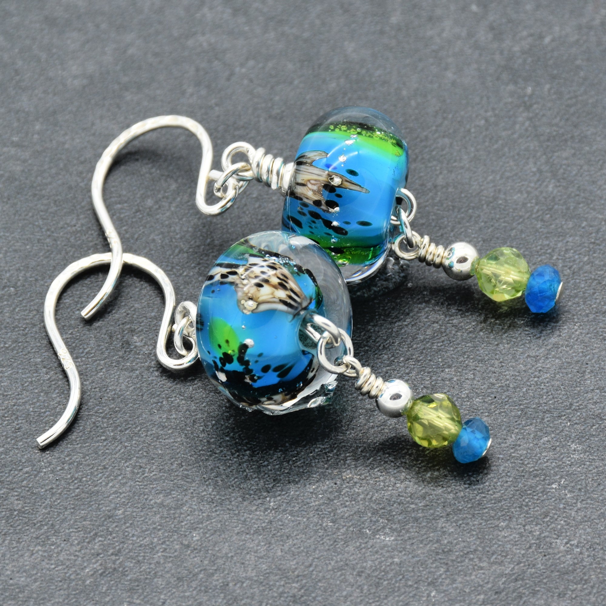 Colorful artisan lampwork glass earrings with sterling silver ear wires, peridot and apatite on a gray surface - handmade with love by Ruby Acorn