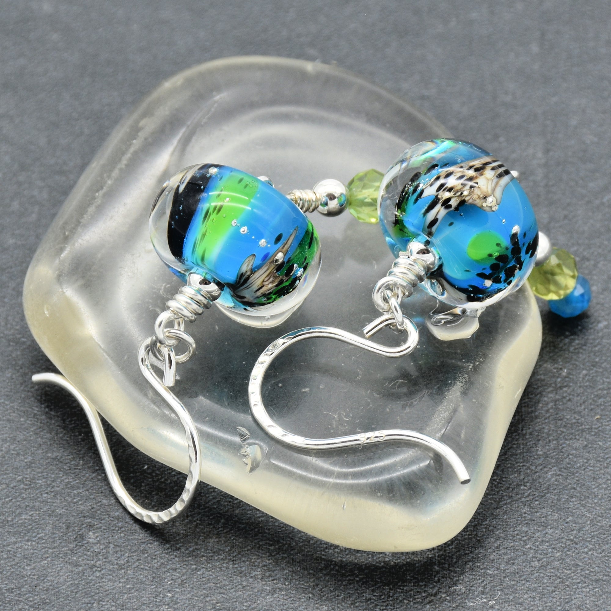 Colorful artisan lampwork glass earrings with sterling silver ear wires, peridot and apatite on a glass surface - handmade with love by Ruby Acorn