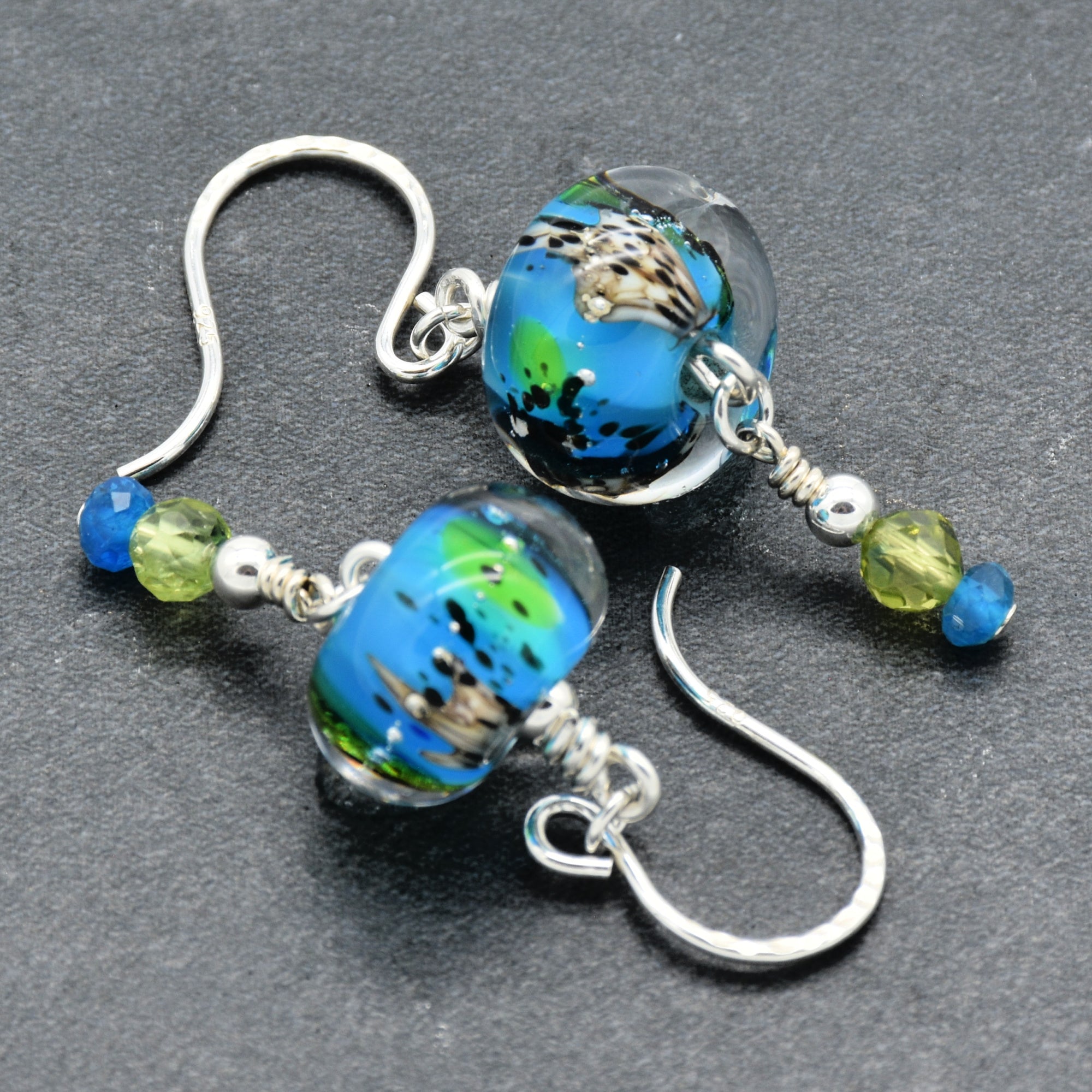 Colorful artisan lampwork glass earrings with sterling silver ear wires, peridot and apatite on a gray surface - handmade with love by Ruby Acorn