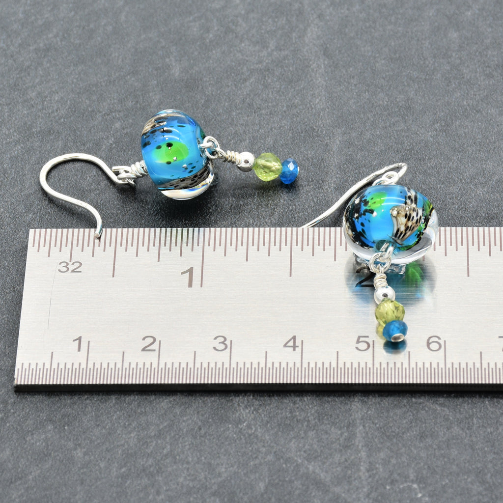 Colorful artisan lampwork glass earrings with sterling silver ear wires, peridot and apatite beside a ruler for scale - handmade with love by Ruby Acorn