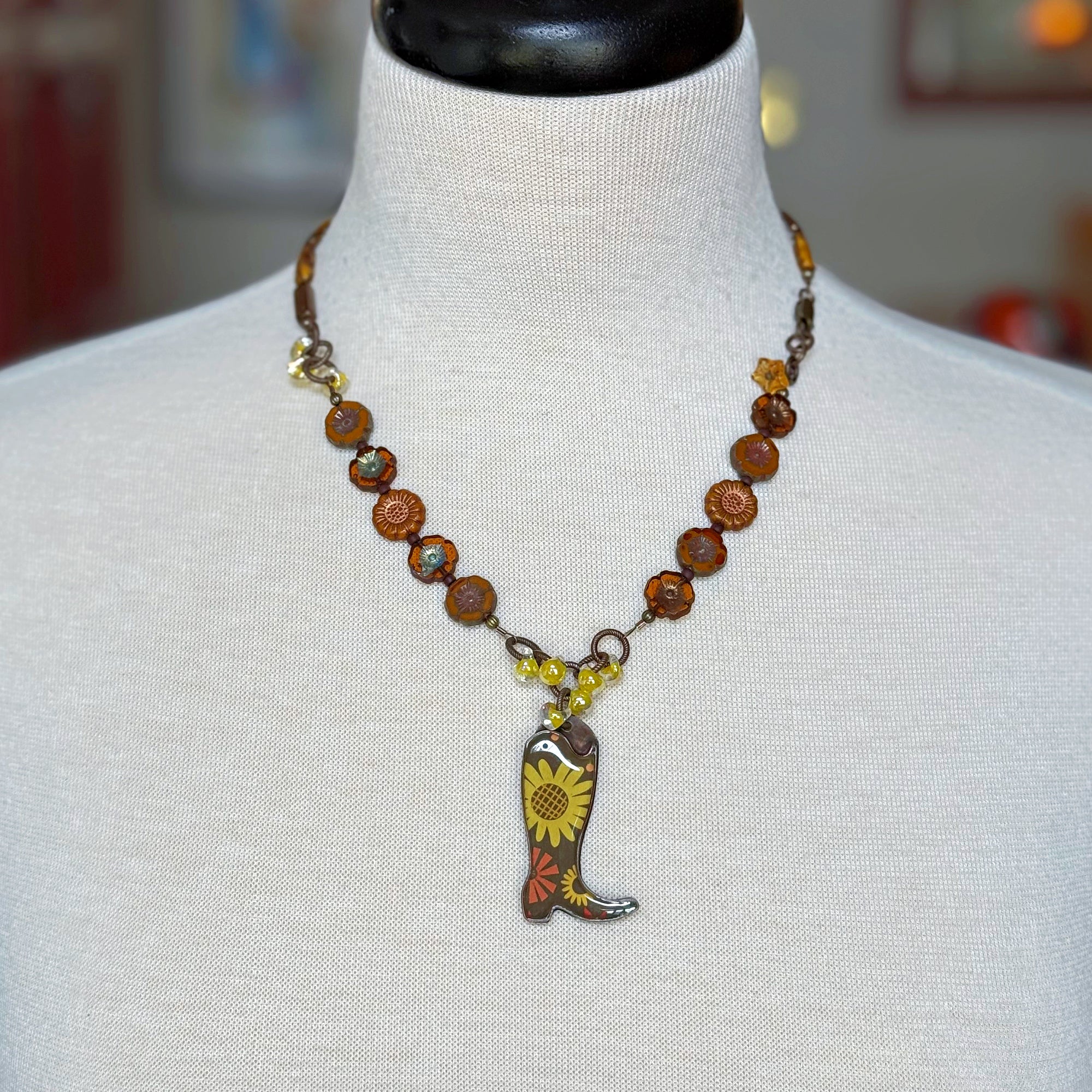 Necklace with cowboy boot and sunflower pendant on a mannequin