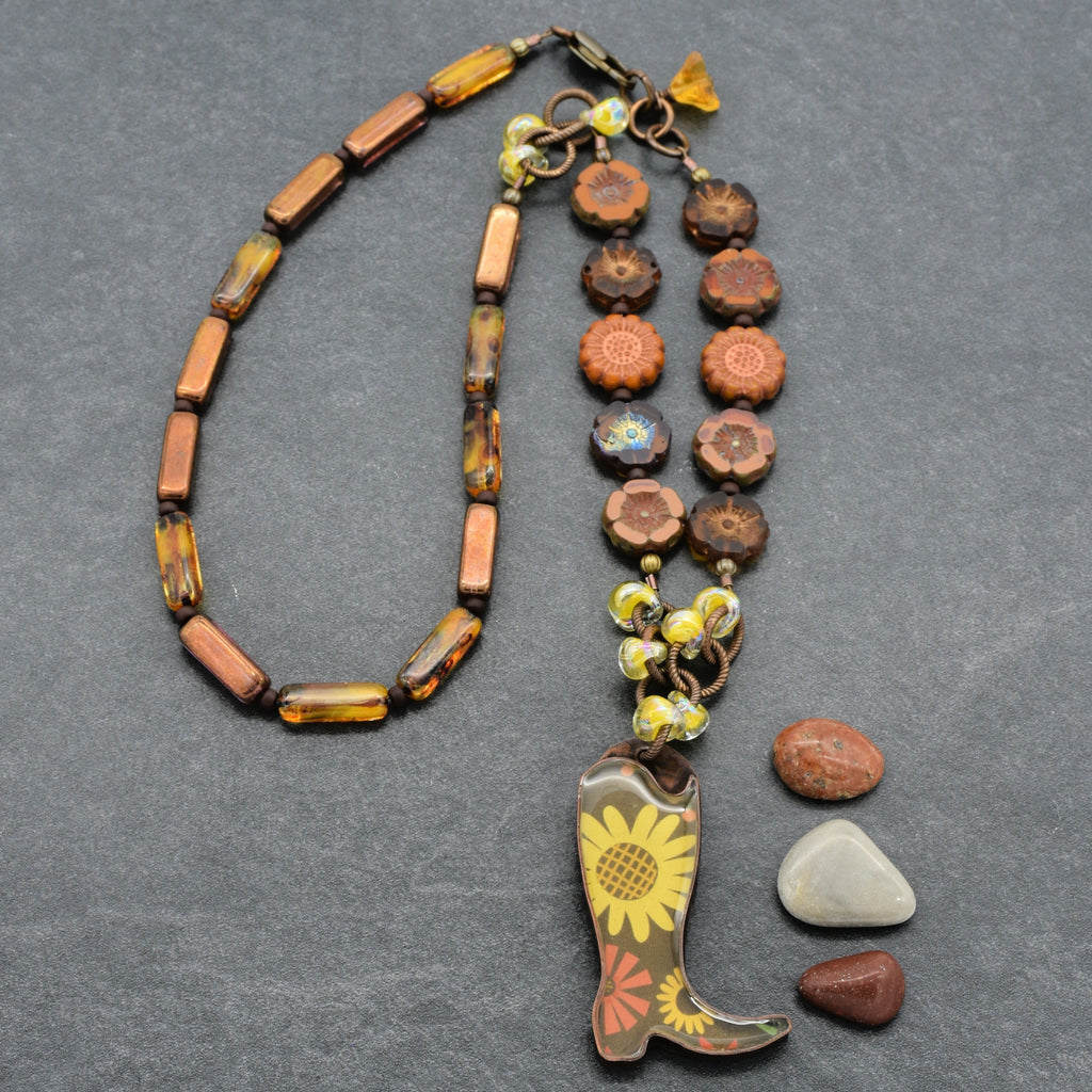 Necklace with cowboy boot pendant and assorted beads on a gray background