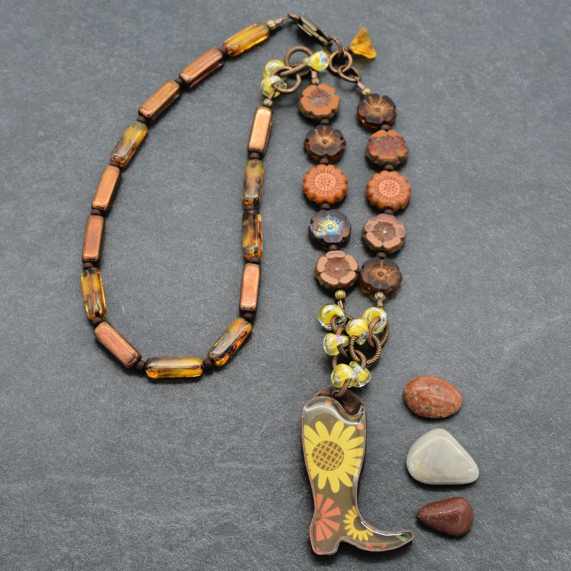 Necklace with cowboy boot pendant and assorted beads on a gray background