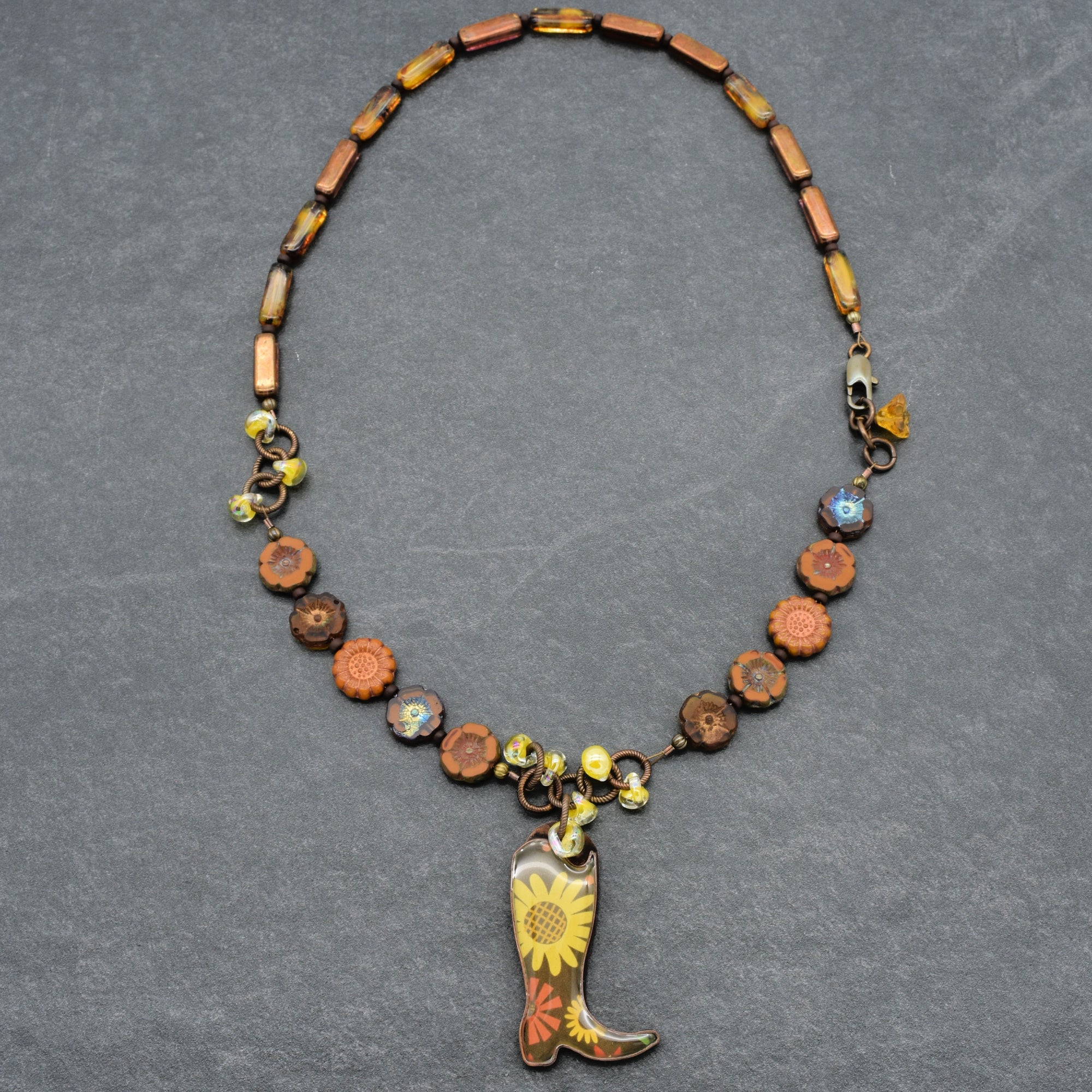 Necklace with cowboy boot pendant and floral design on a gray background