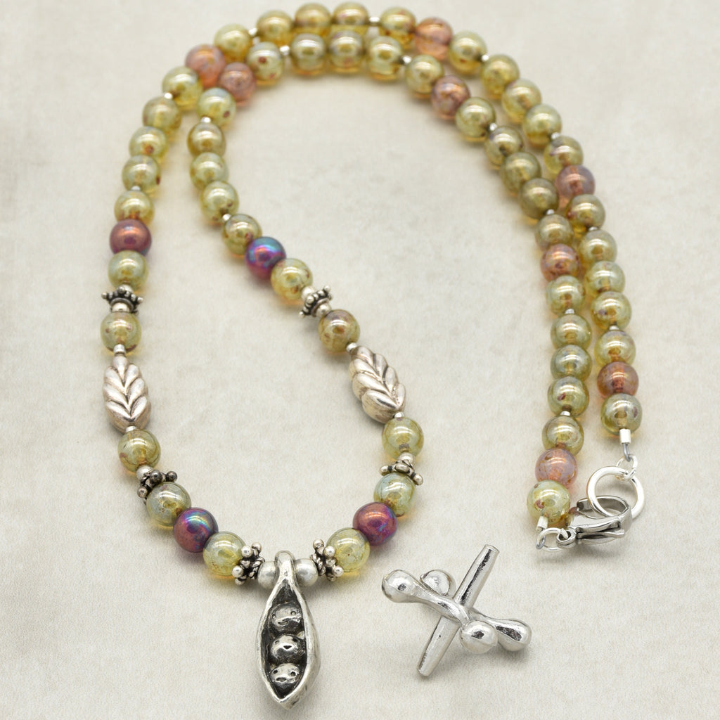 Necklace with green beads and pewter peapod focal on a light background