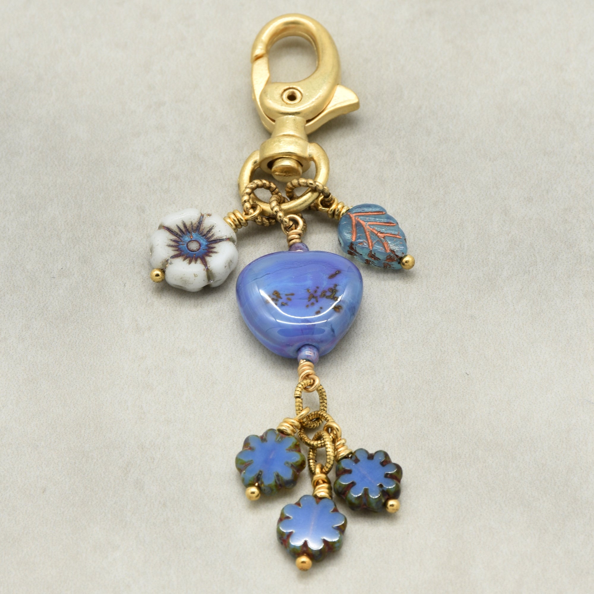 Gold charm with blue and white floral beads on a beige background