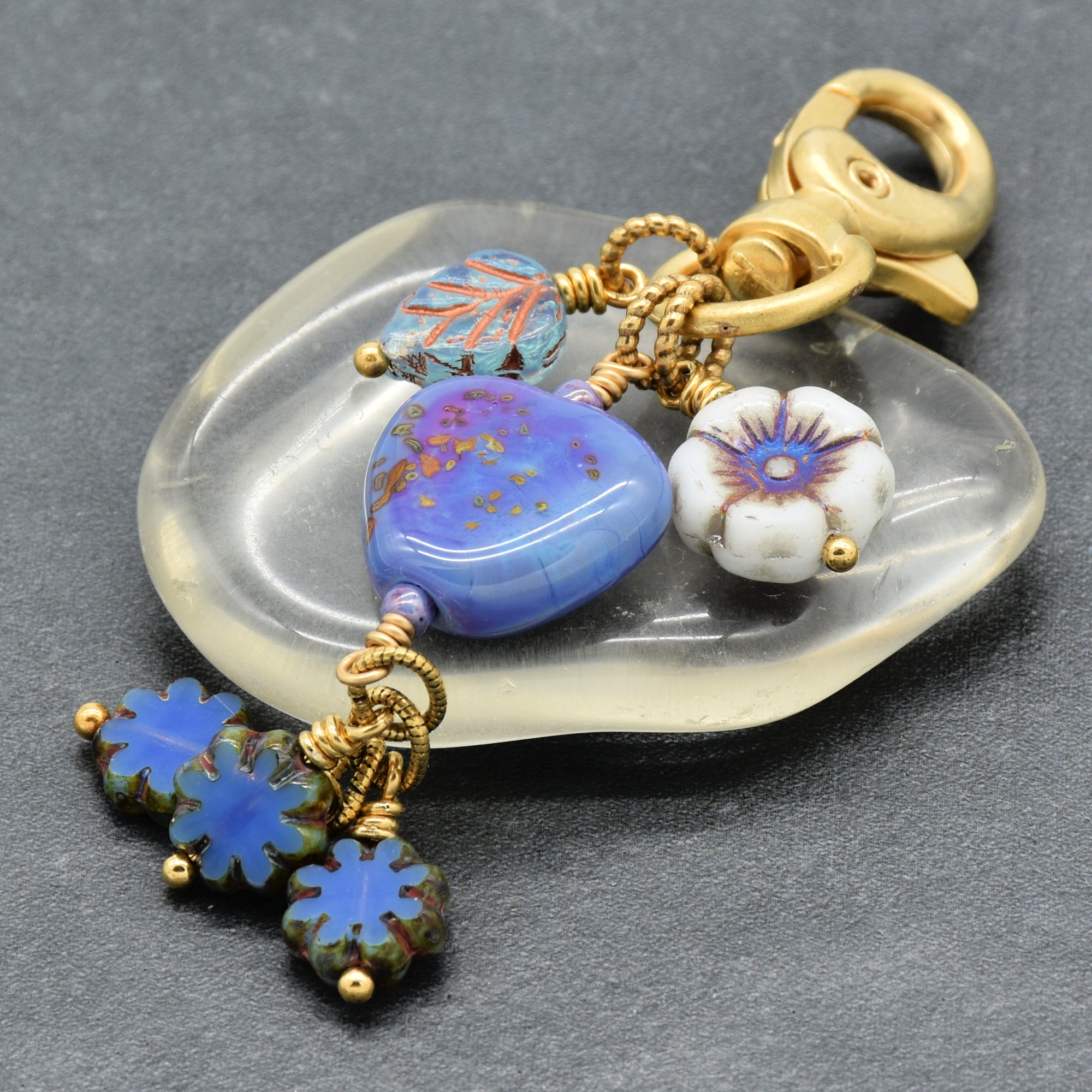 Decorative keychain with colorful beads and gold accents on a gray background