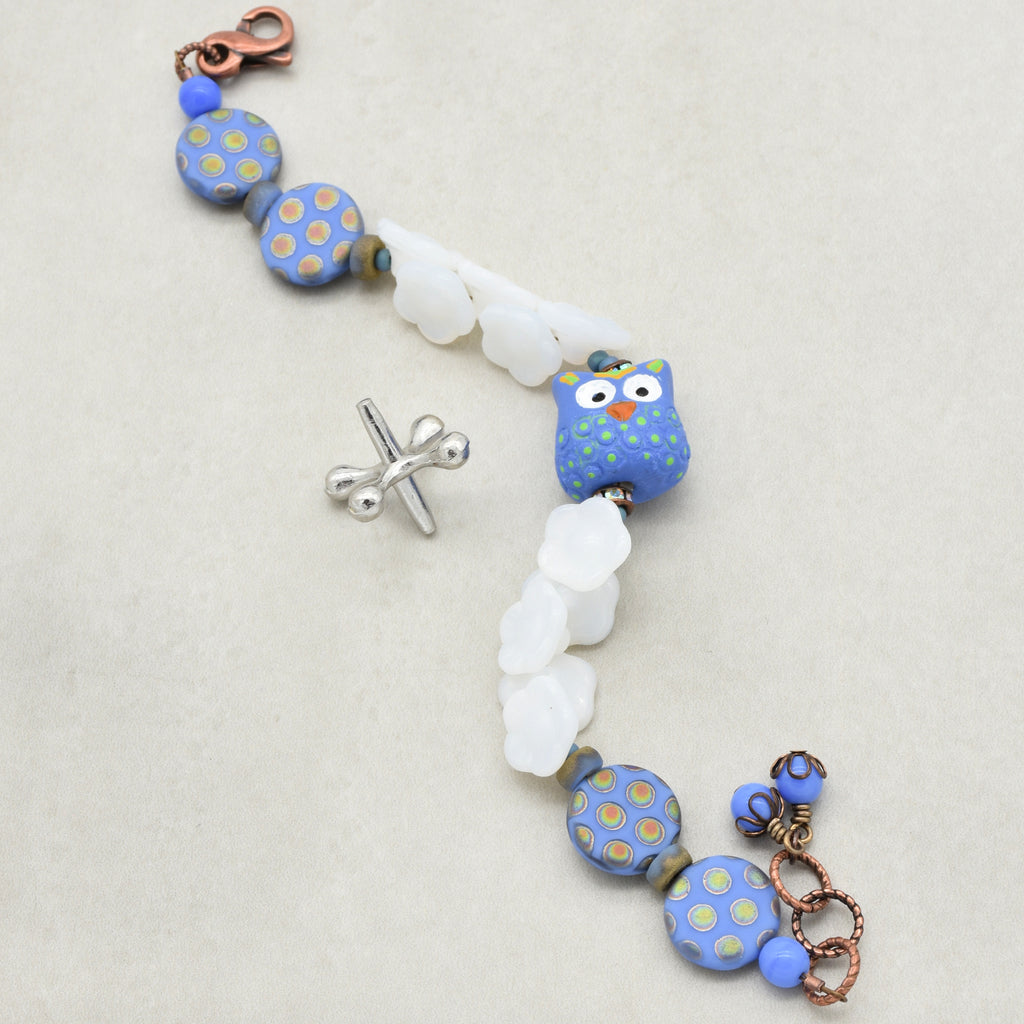 Bracelet with blue and white polka dot beads and owl focal on a light background