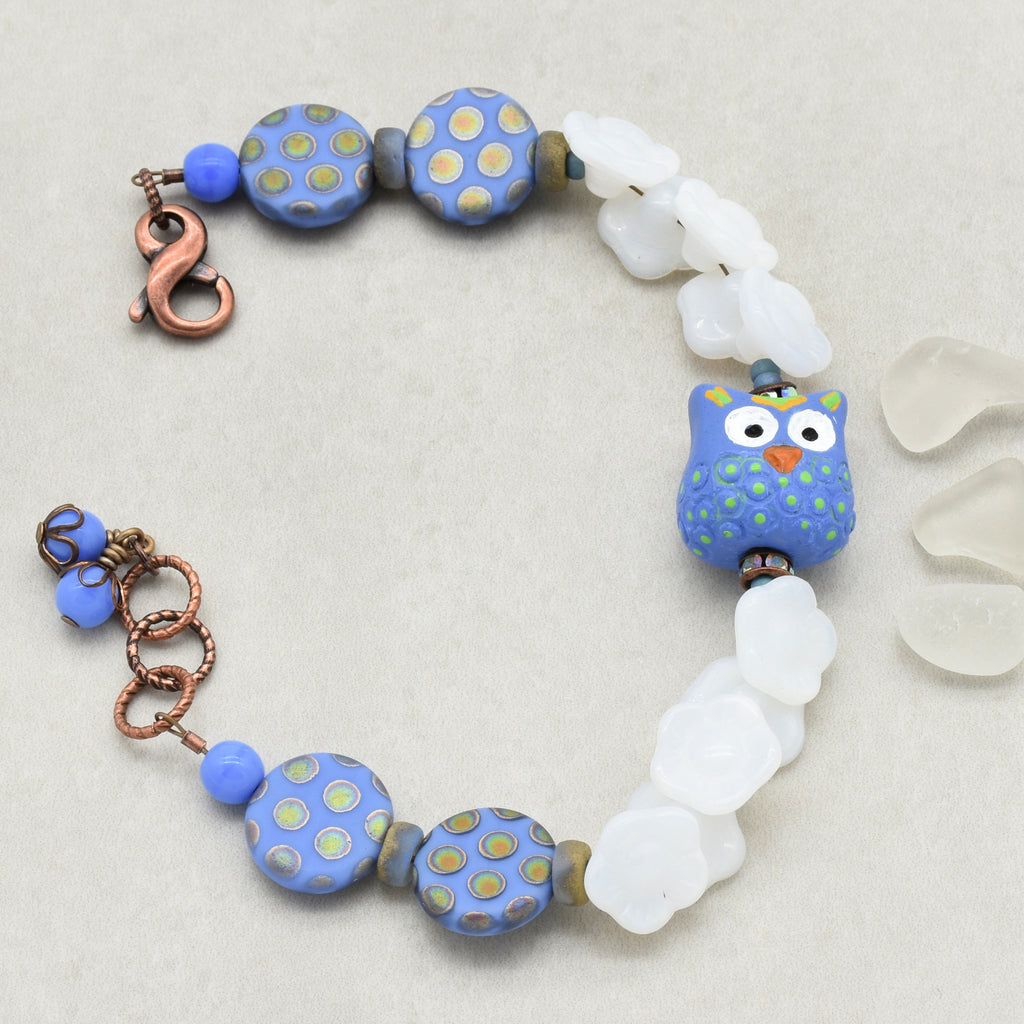 Bracelet with blue polka dot beads and owl focal on a light gray background
