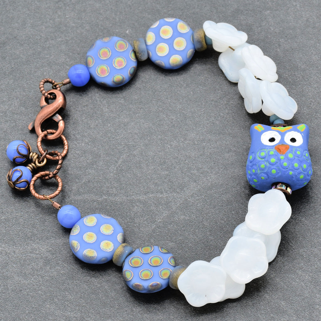 Bracelet with periwinkle polka dot beads and owl focal on a gray background