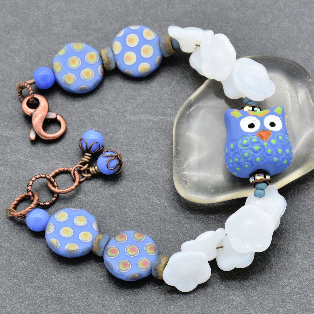 Beaded bracelet with owl focal on a gray surface