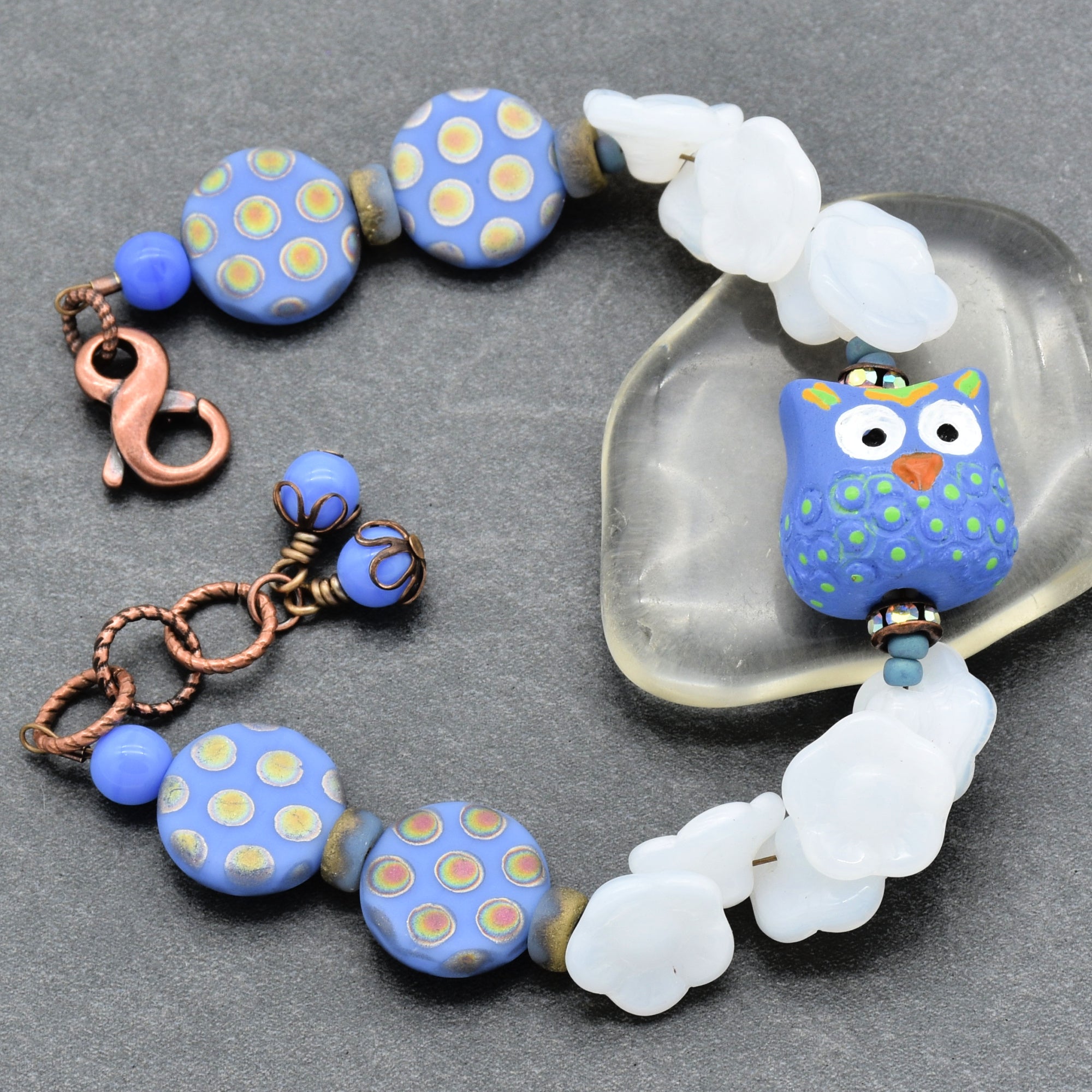 Beaded bracelet with owl focal on a gray surface