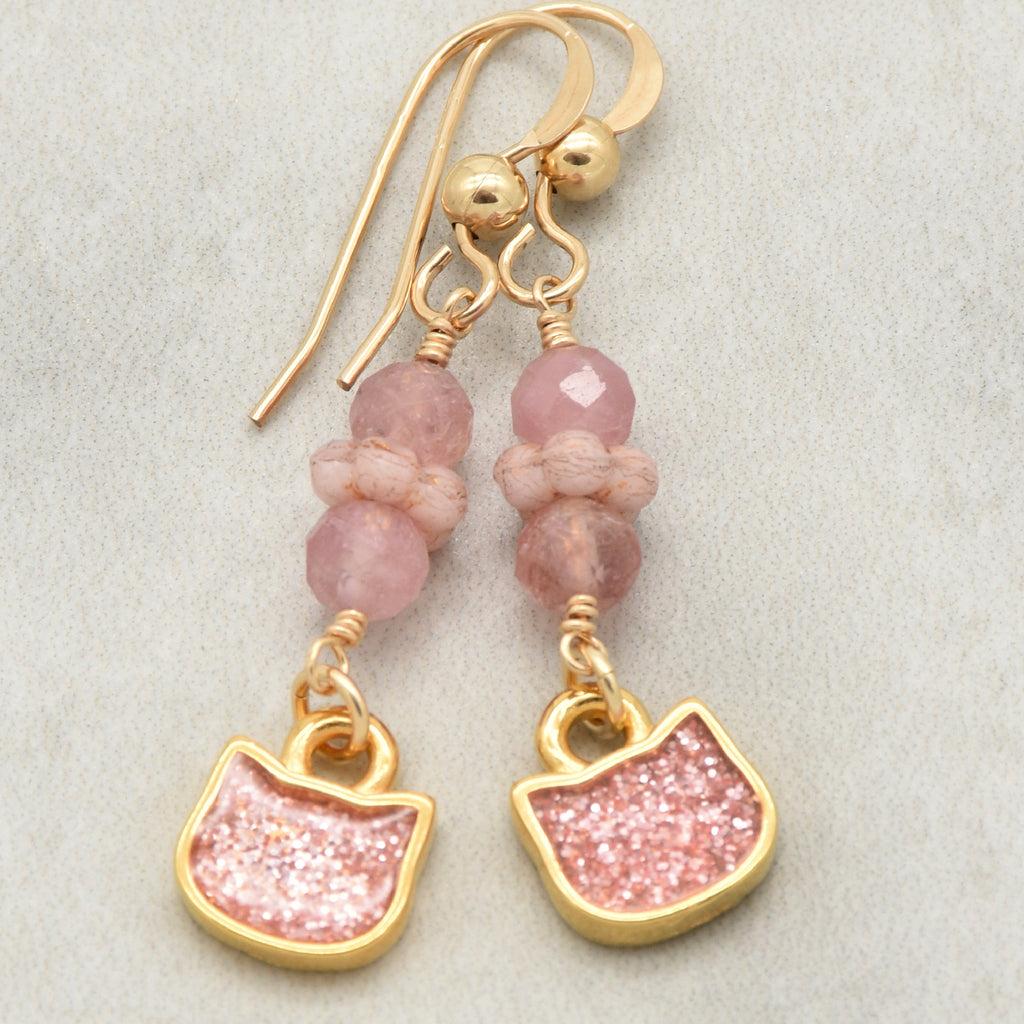 Lovely delicate pink dangle earrings with cat charms, pink tourmaline, and gold ear wires on a light background - handmade with love by Ruby Acorn