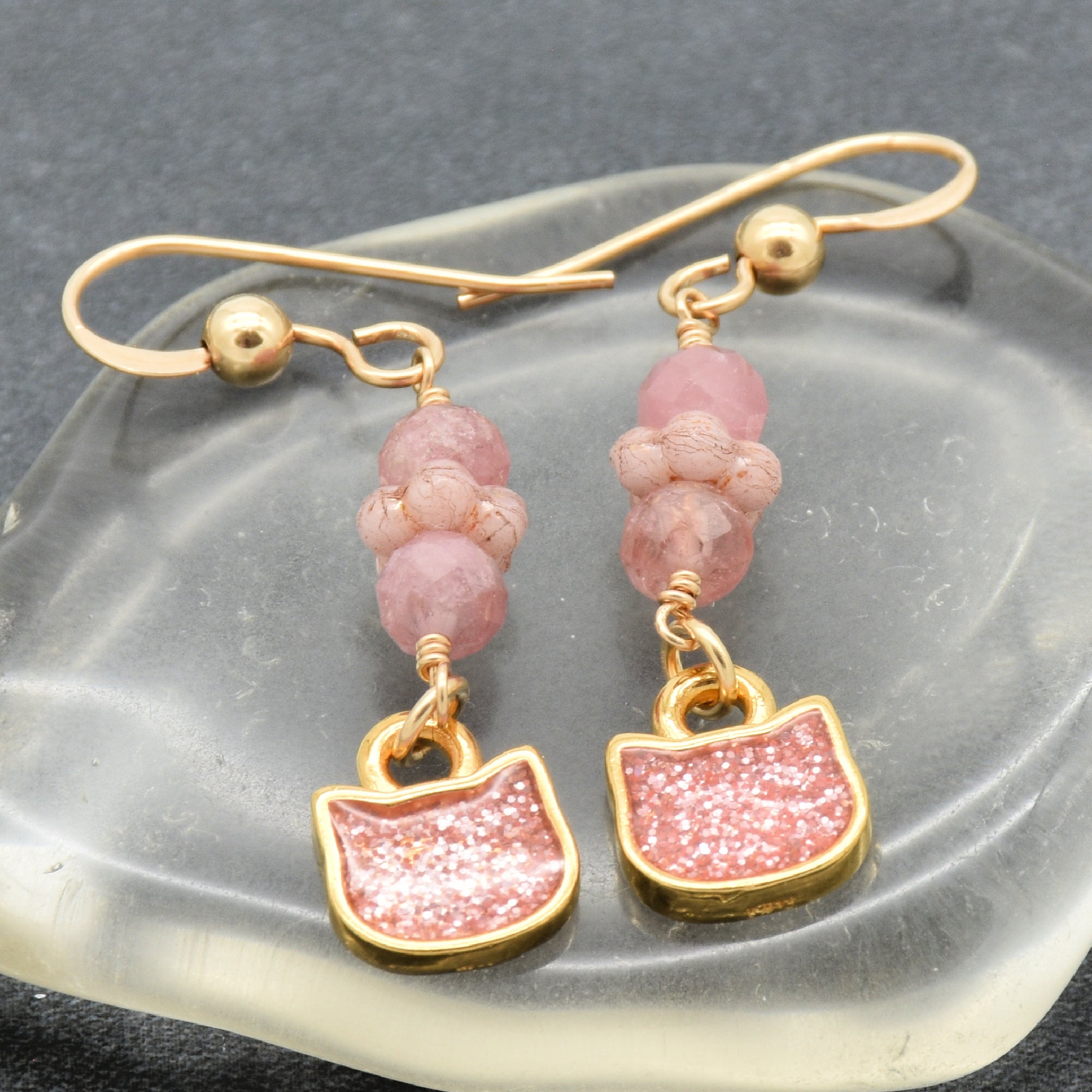 Lovely delicate pink dangle earrings with cat charms, pink tourmaline, and gold ear wires on a glass background - handmade with love by Ruby Acorn