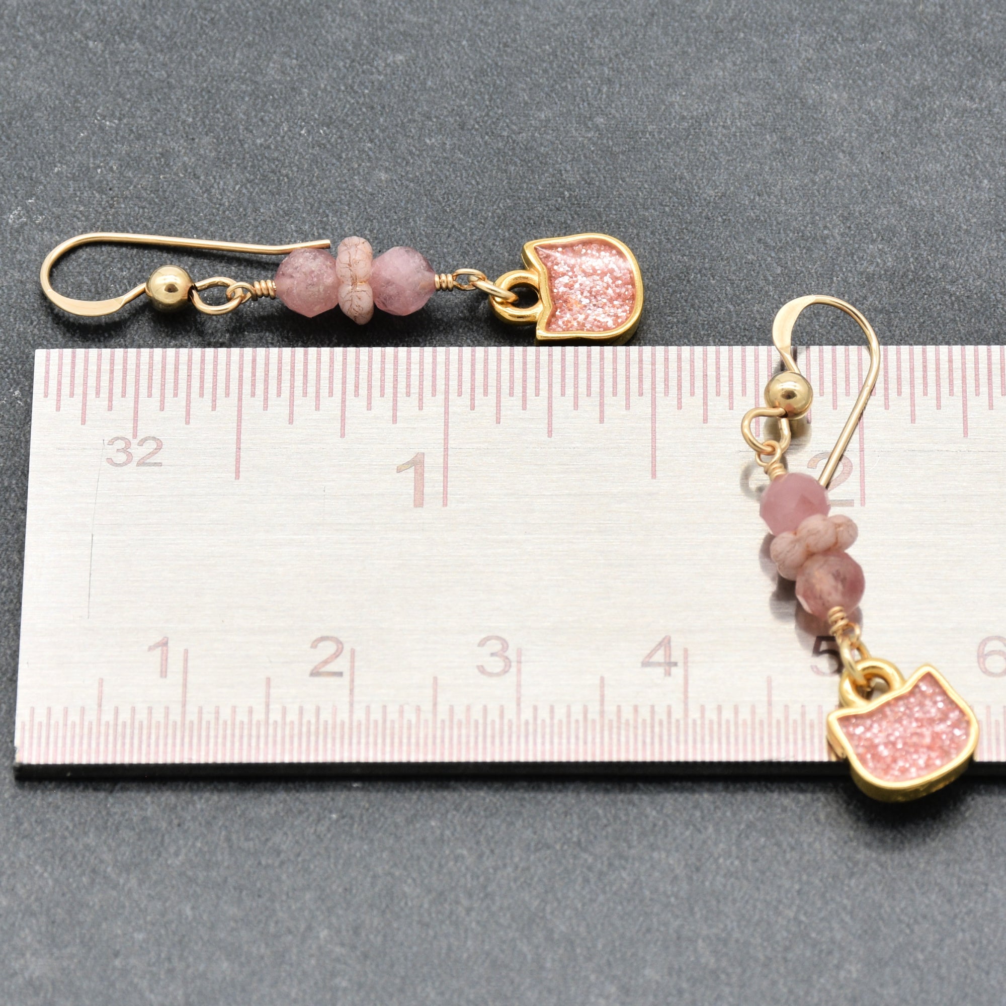 Lovely delicate pink dangle earrings with cat charms, pink tourmaline, and gold ear wires beside a ruler for scale - handmade with love by Ruby Acorn