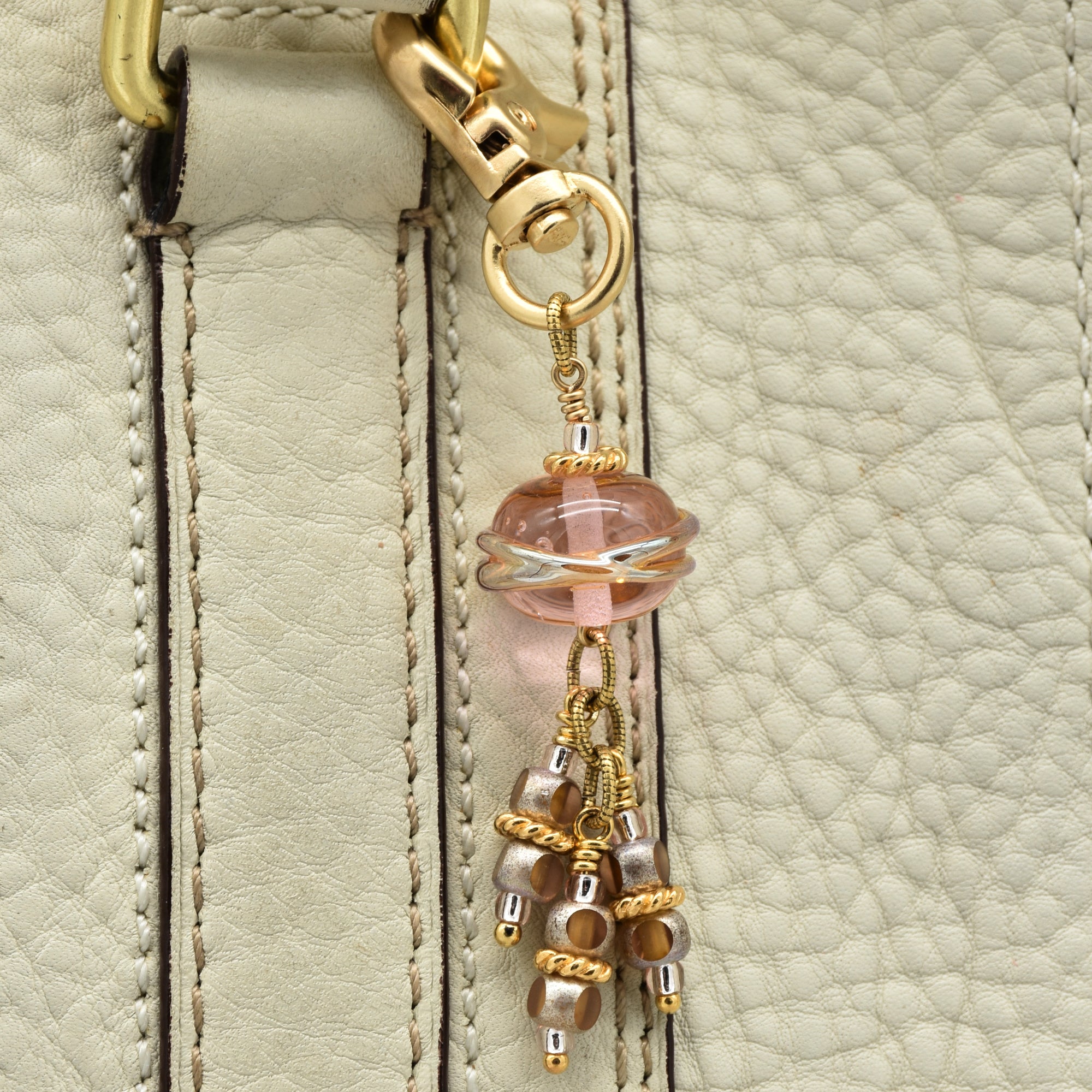 Beaded keychain attached to a beige leather bag