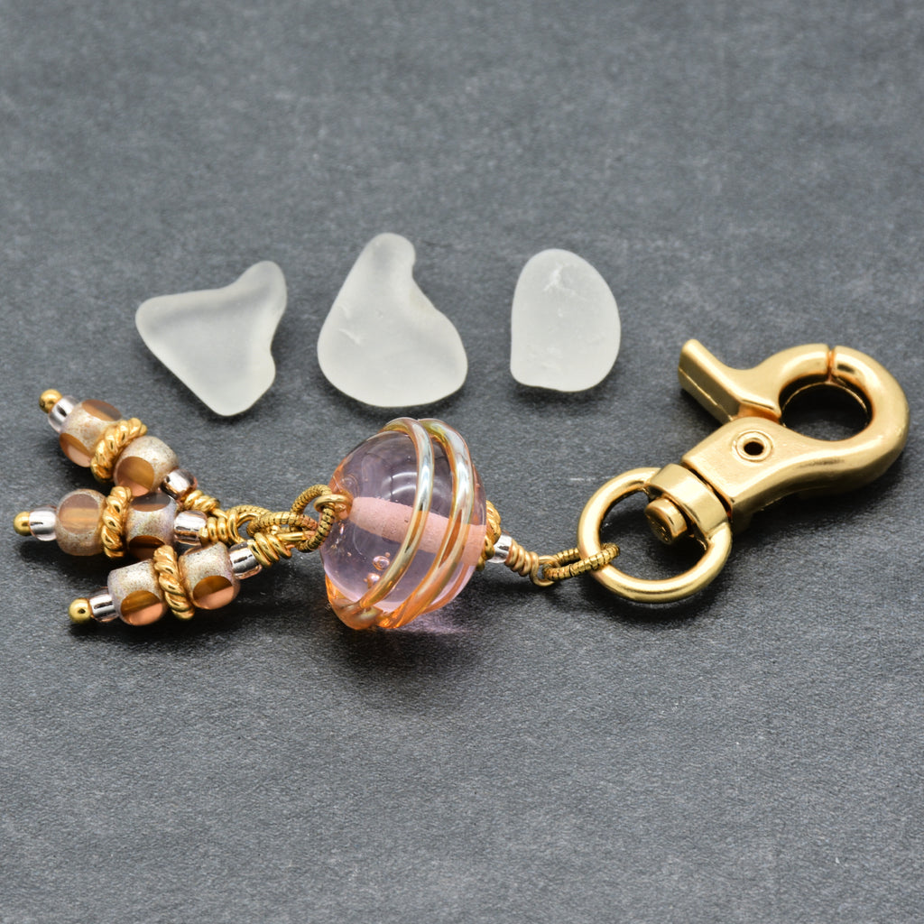Jewelry charm with decorative beads and a gold clasp on a gray background