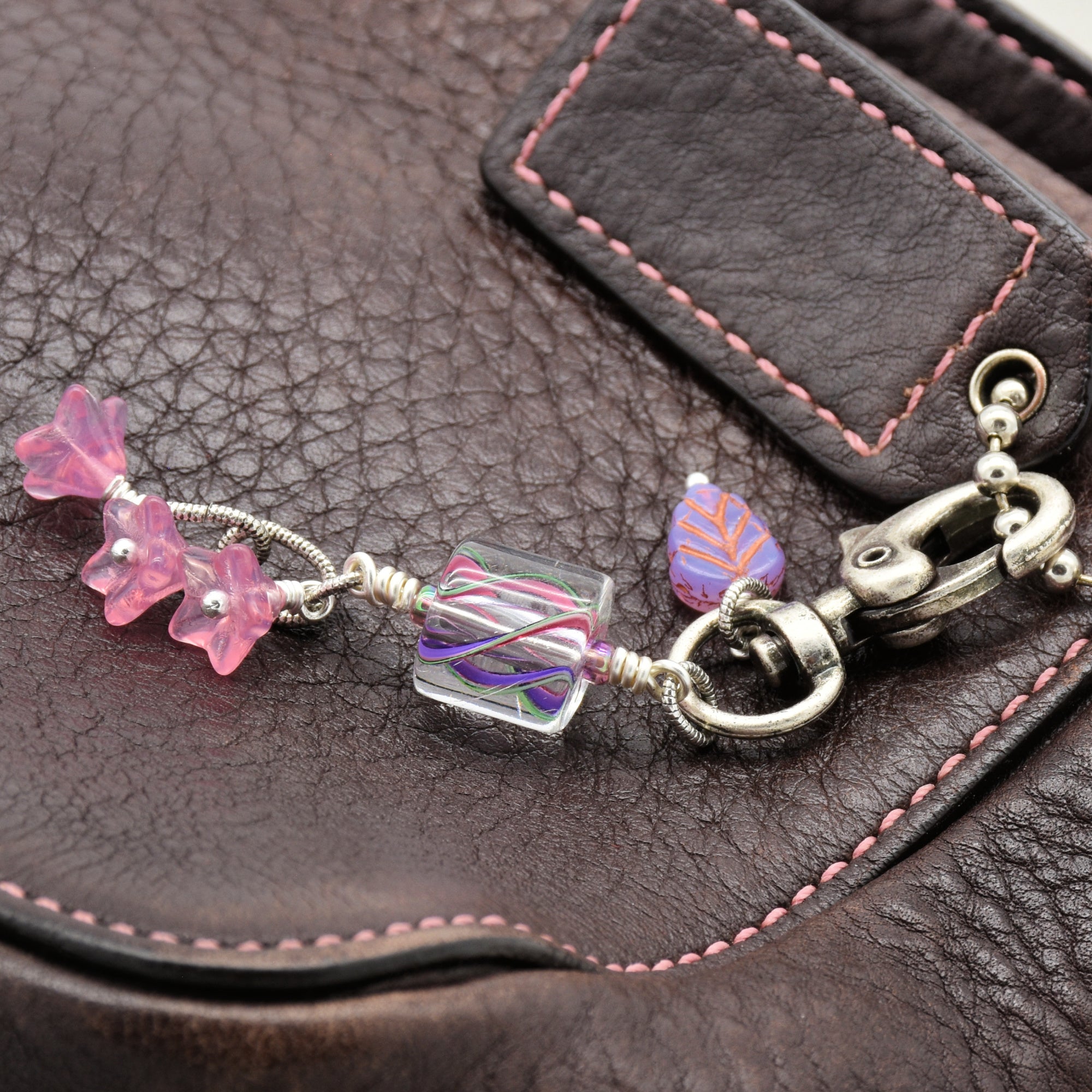 Keychain with pink cane glass and Czech glass charms  on a brown leather surface