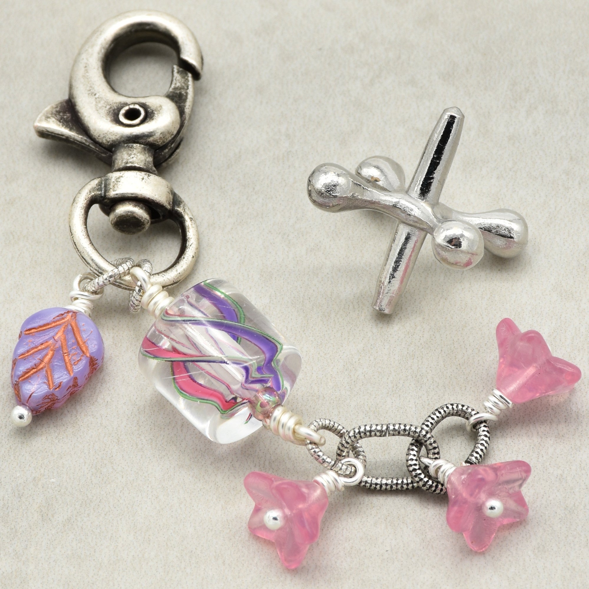 Silver charm with colorful beads on a light gray background