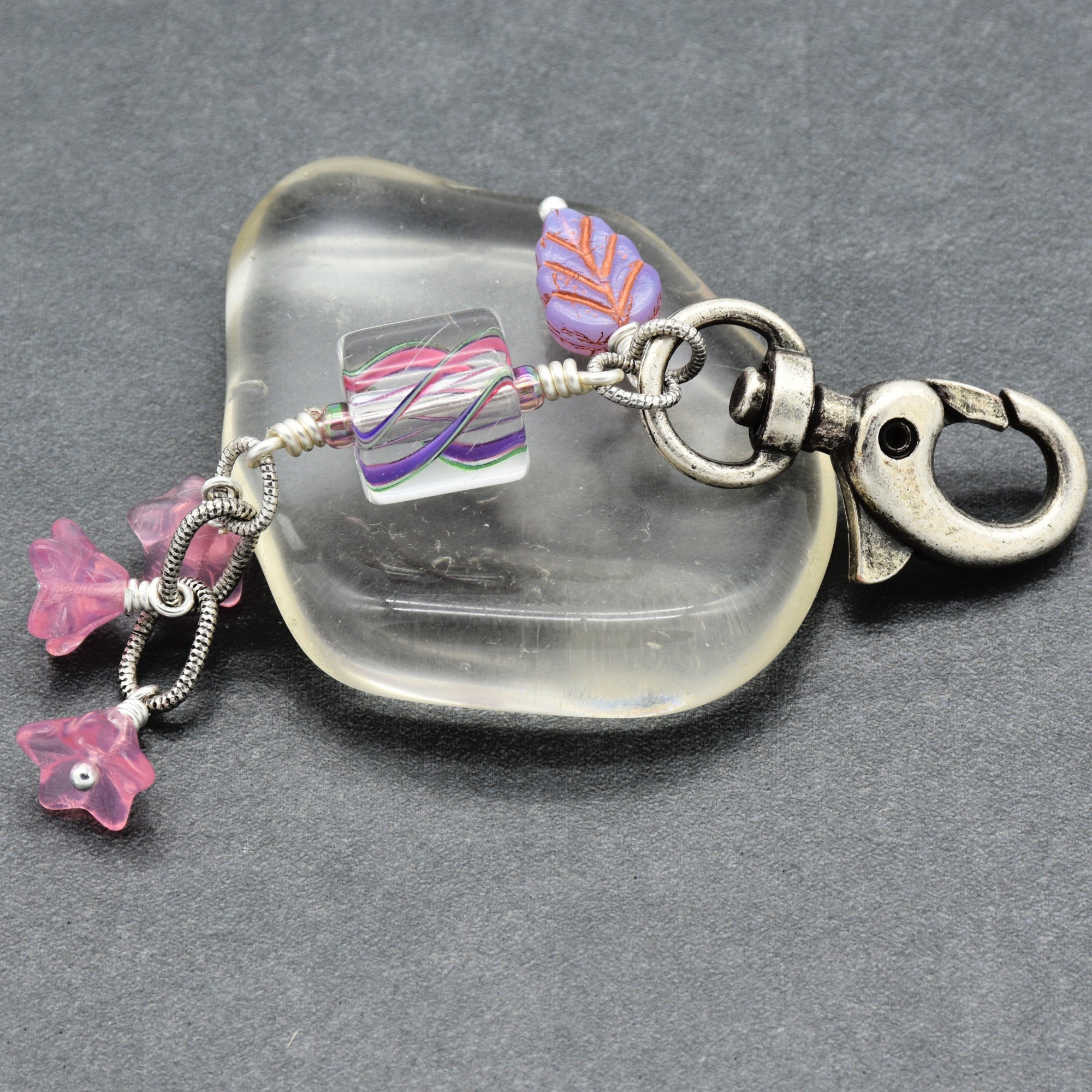 Keychain with silver clasp and pink floral charms on a gray background