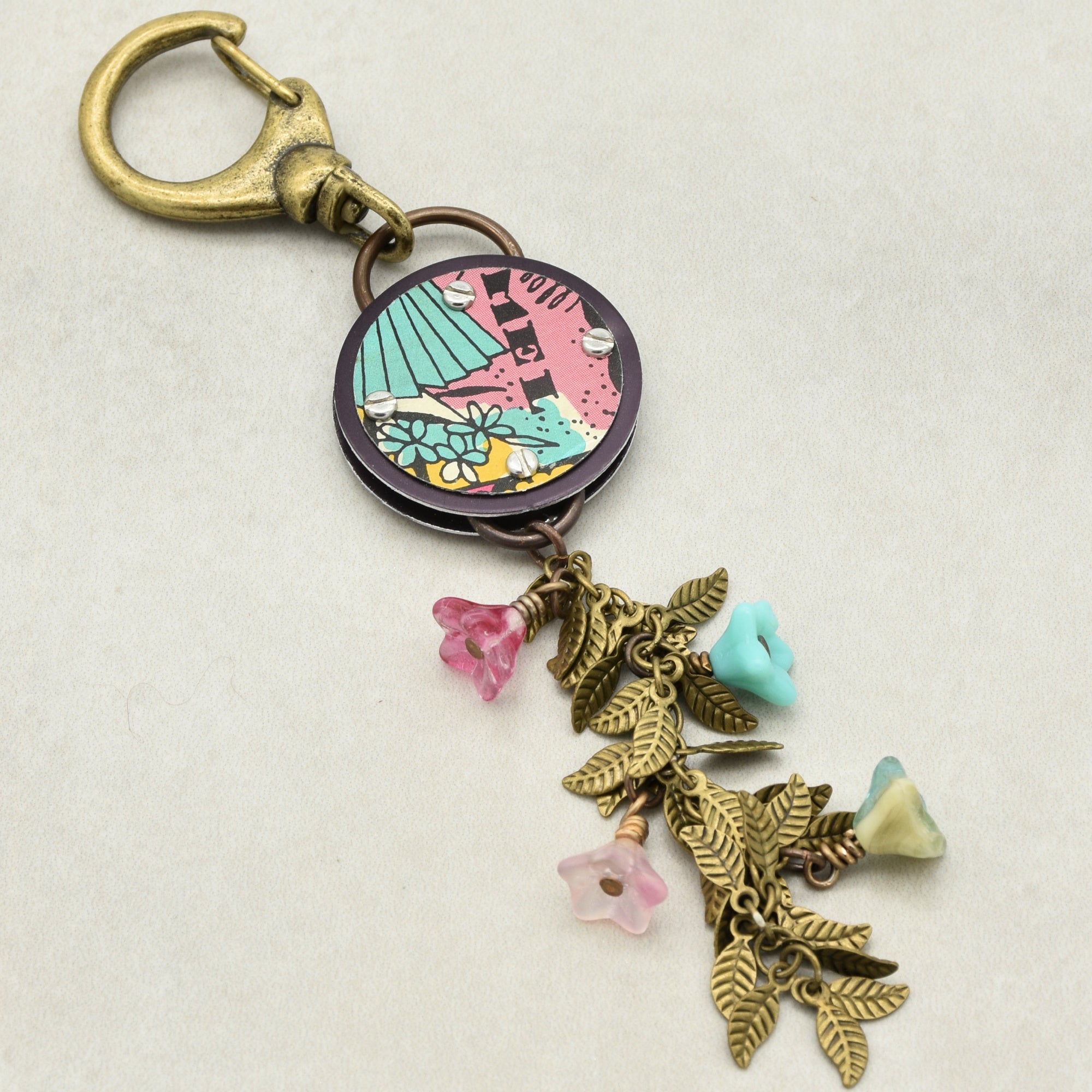 Decorative handbag charm with colorful pendant and charms on a light background