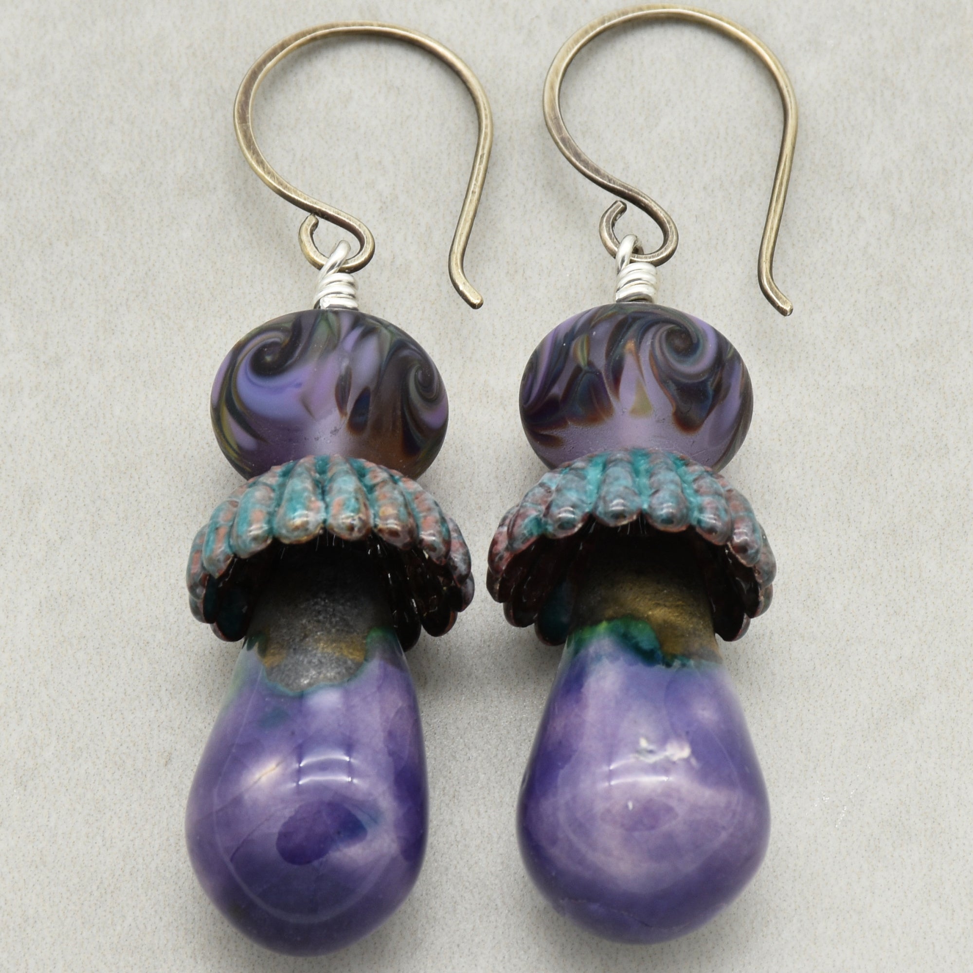 Pair of purple swirl earrings with sterling silver ear wires on a light gray background