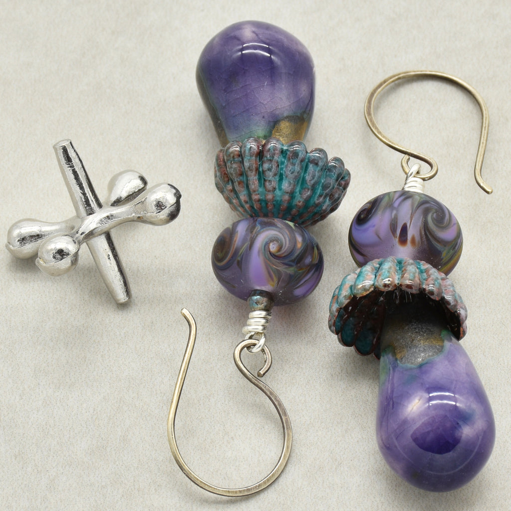 Pair of purple and teal earrings on a light gray background