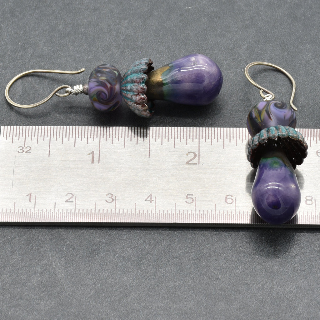 Pair of purple glass bead earrings on a ruler for scale.