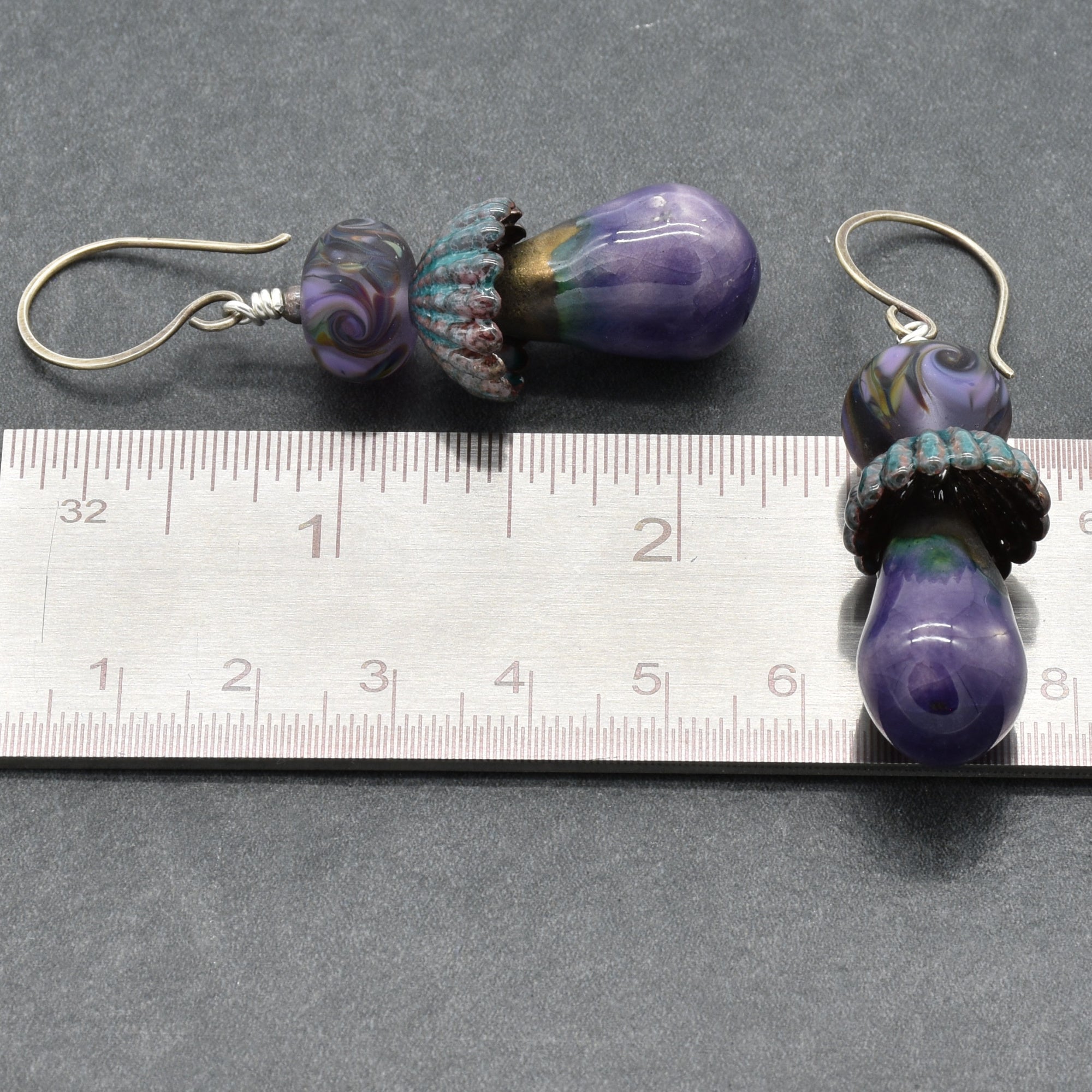 Pair of purple glass bead earrings on a ruler for scale.
