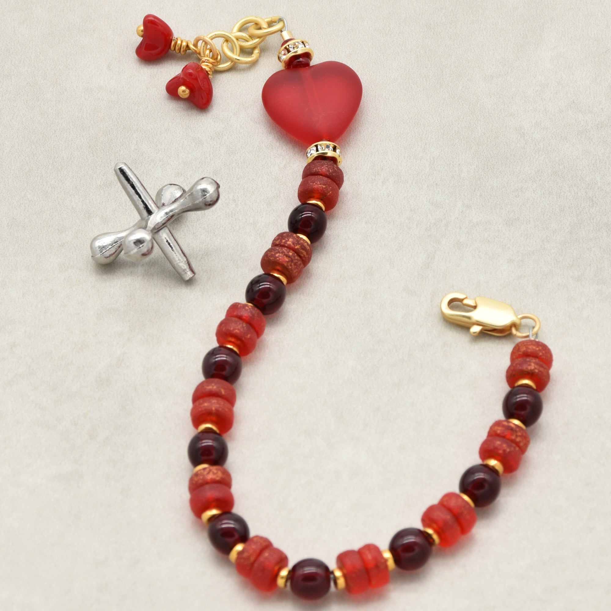 Bracelet with red beads and gold accents on a light background