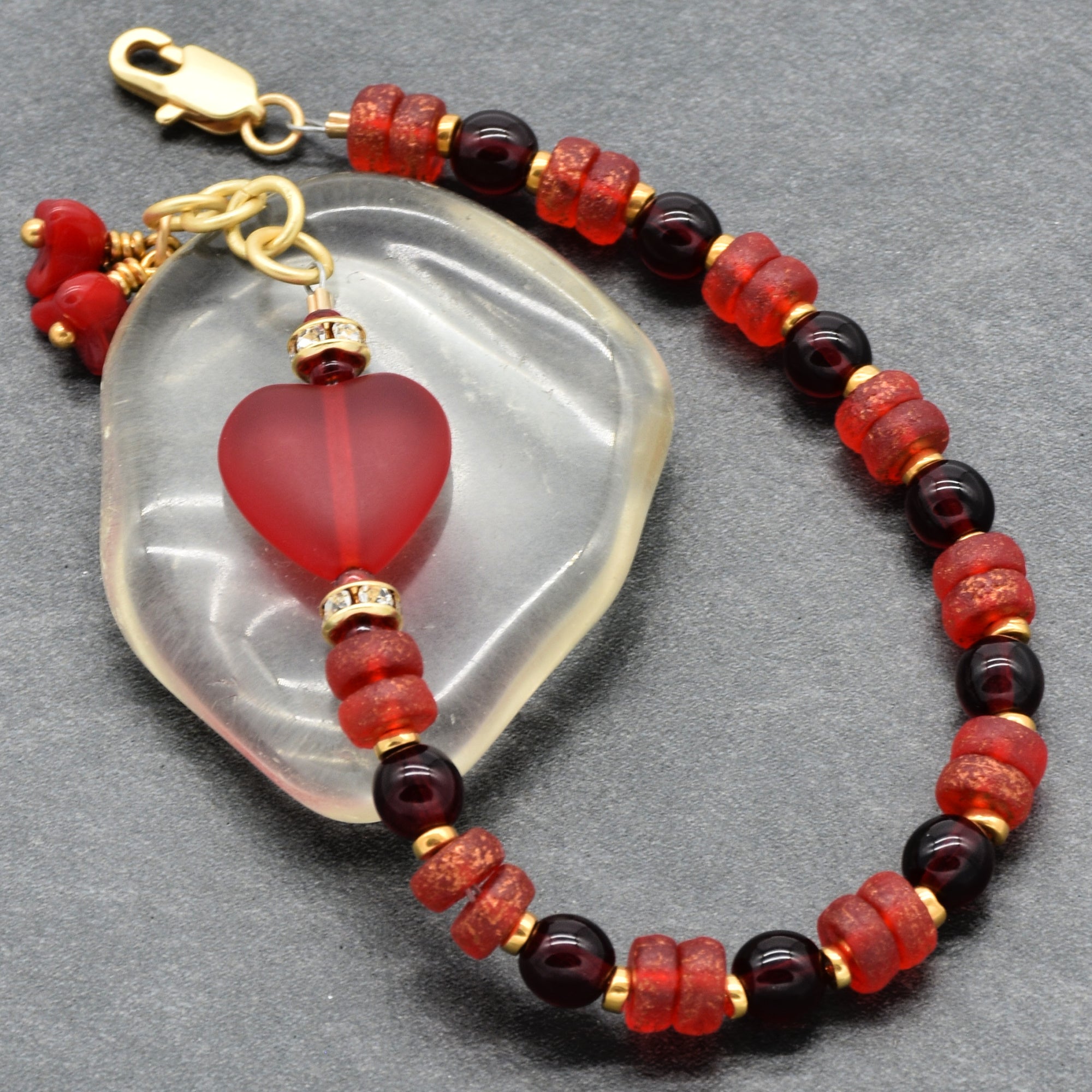 Beaded bracelet with red and gold beads on a gray background