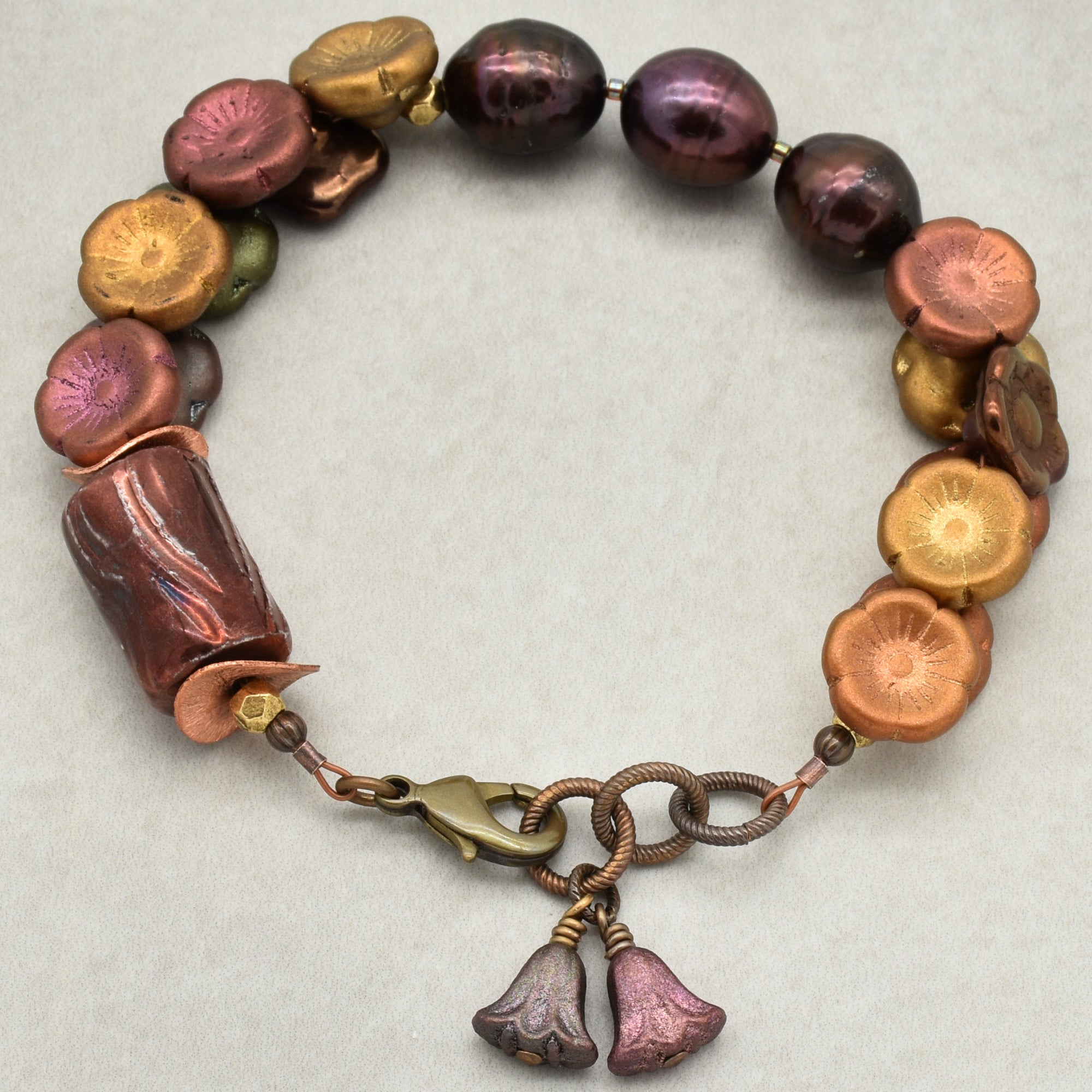 Bracelet with multicolored beads and floral charm on a light background