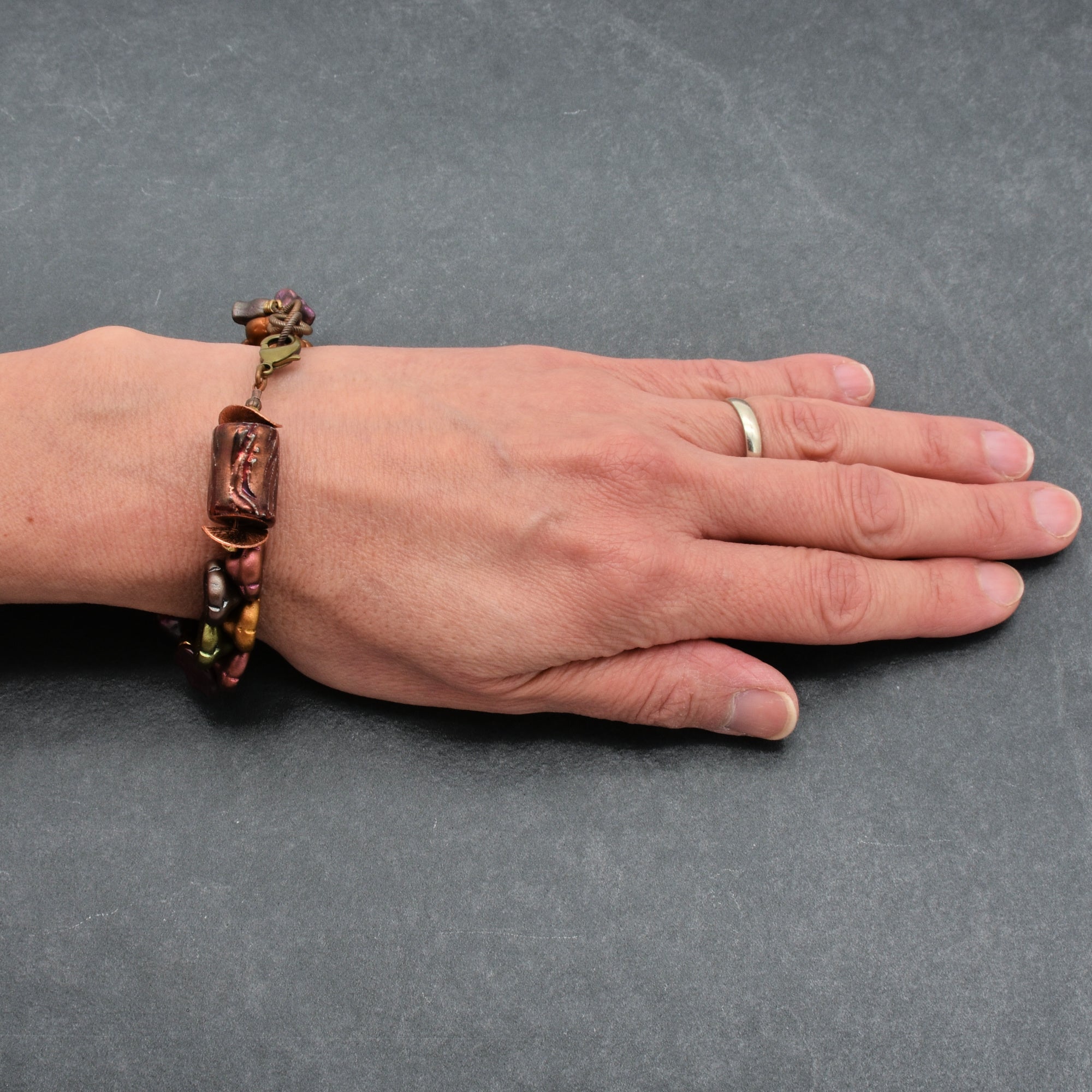 Hand wearing a bracelet on a gray background