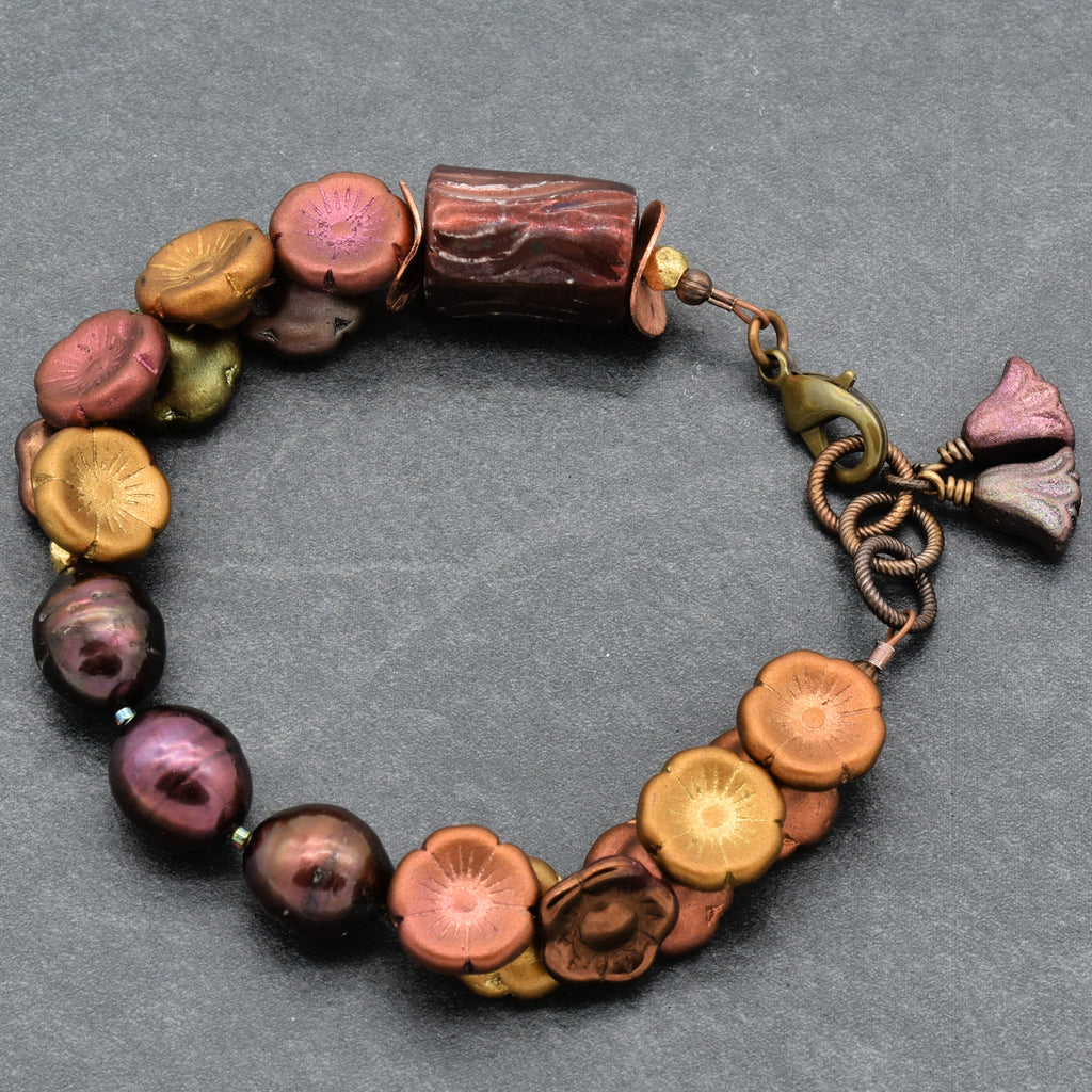 Multicolored beaded bracelet with a floral charm on a gray background