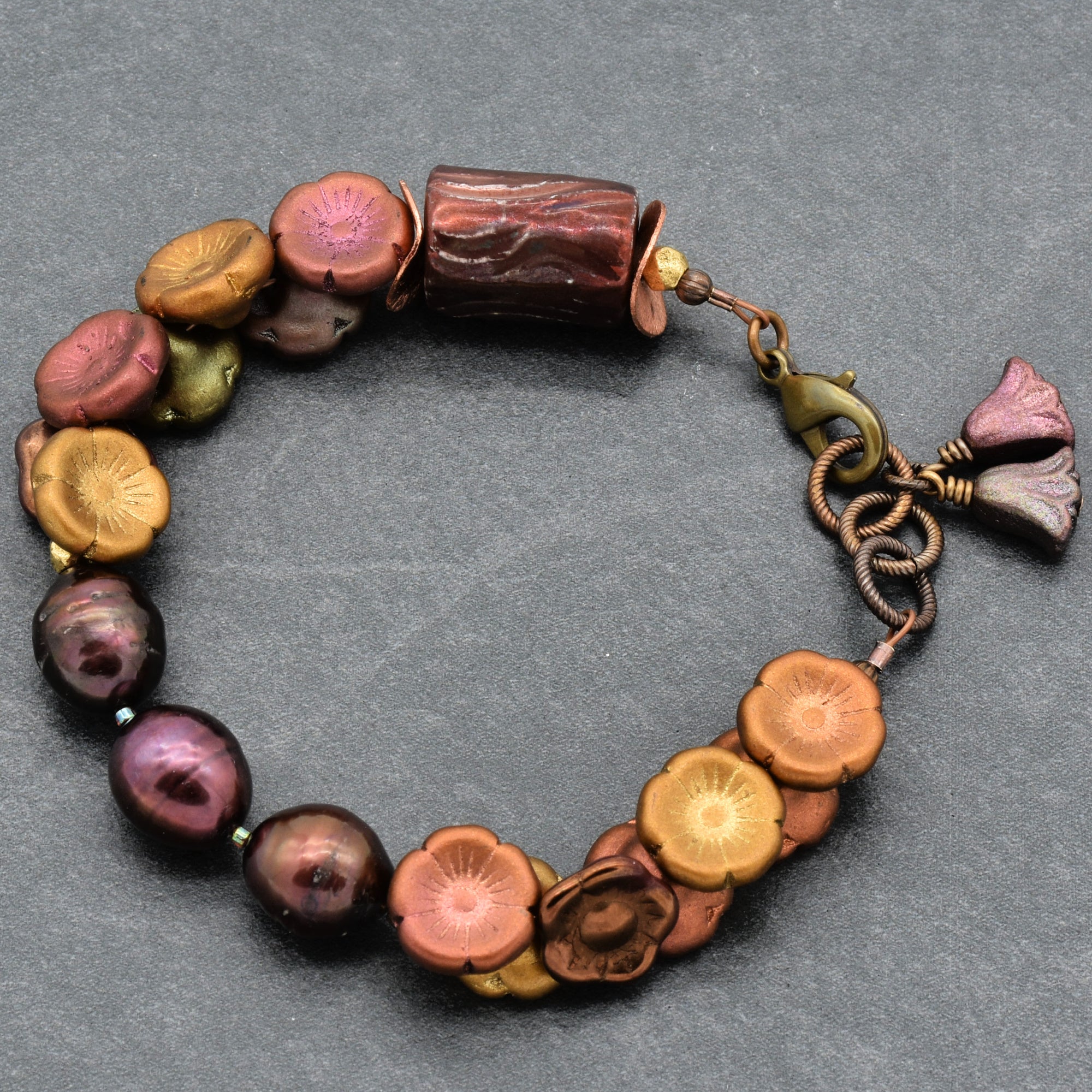 Multicolored beaded bracelet with a floral charm on a gray background