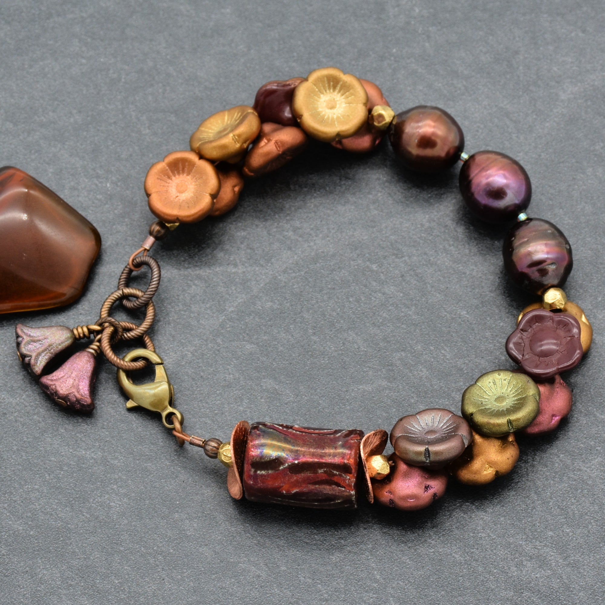Beaded bracelet with colorful beads and floral charms on a gray background