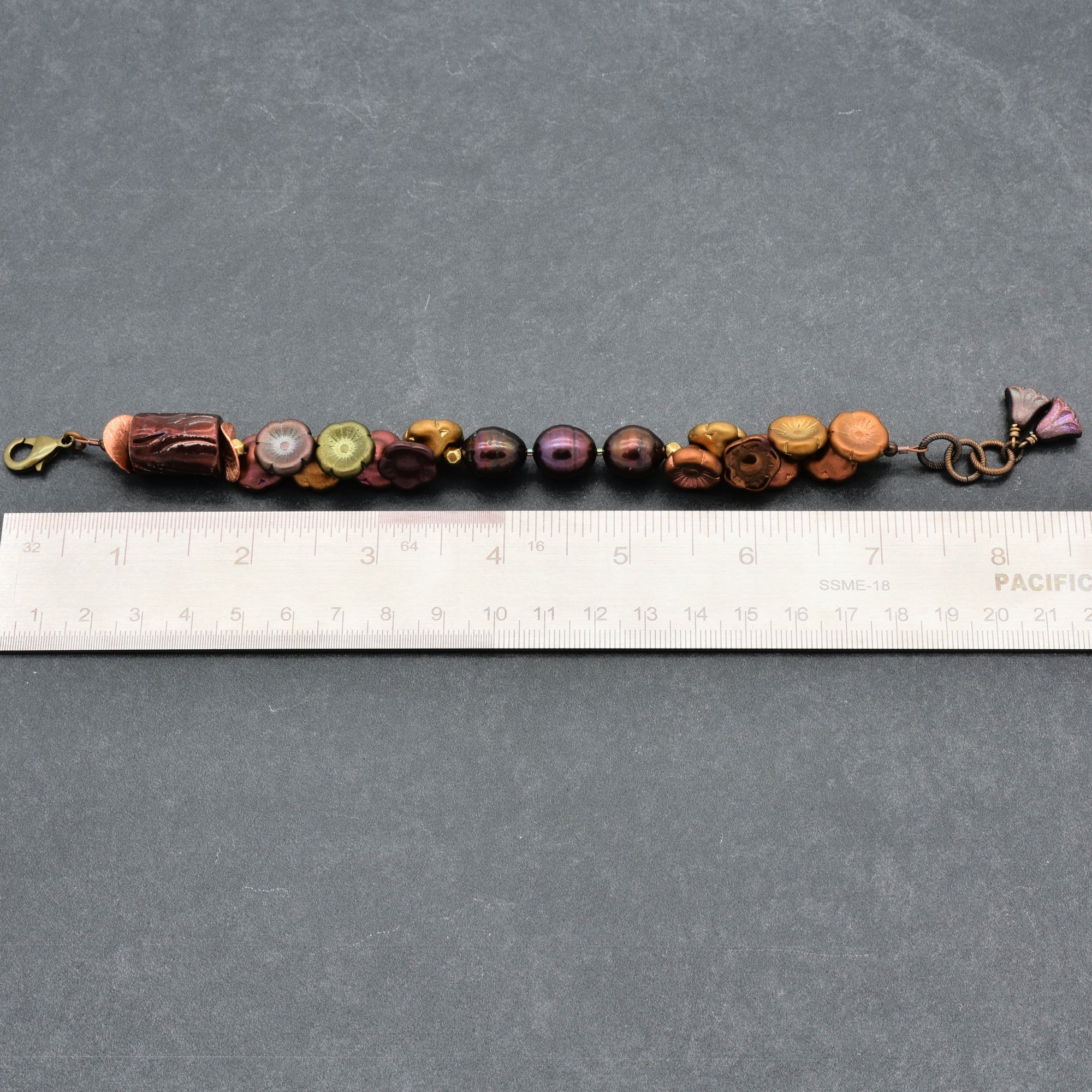 Beaded bracelet with a ruler for scale on a gray background