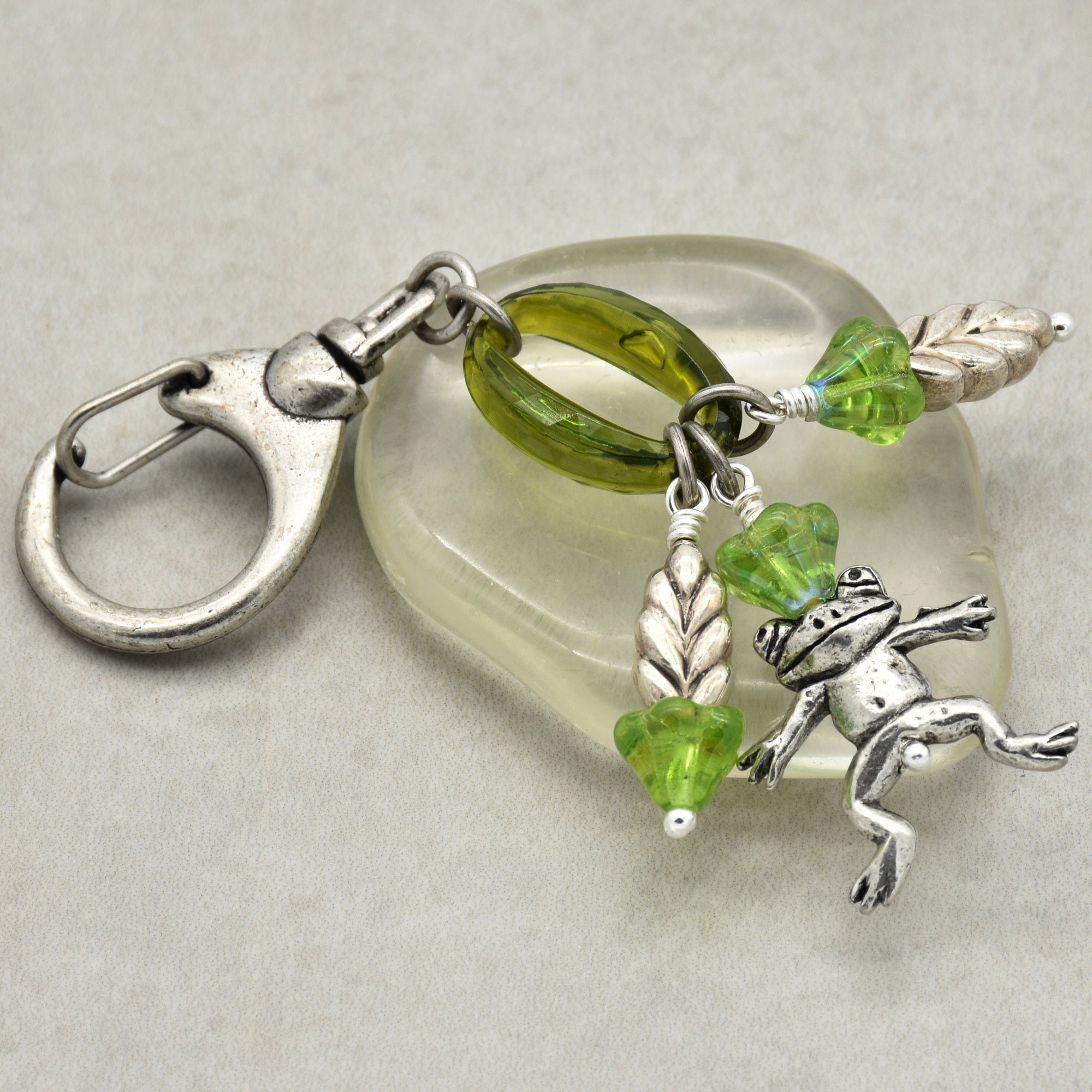 Keychain with green beads and a frog charm on a light gray background