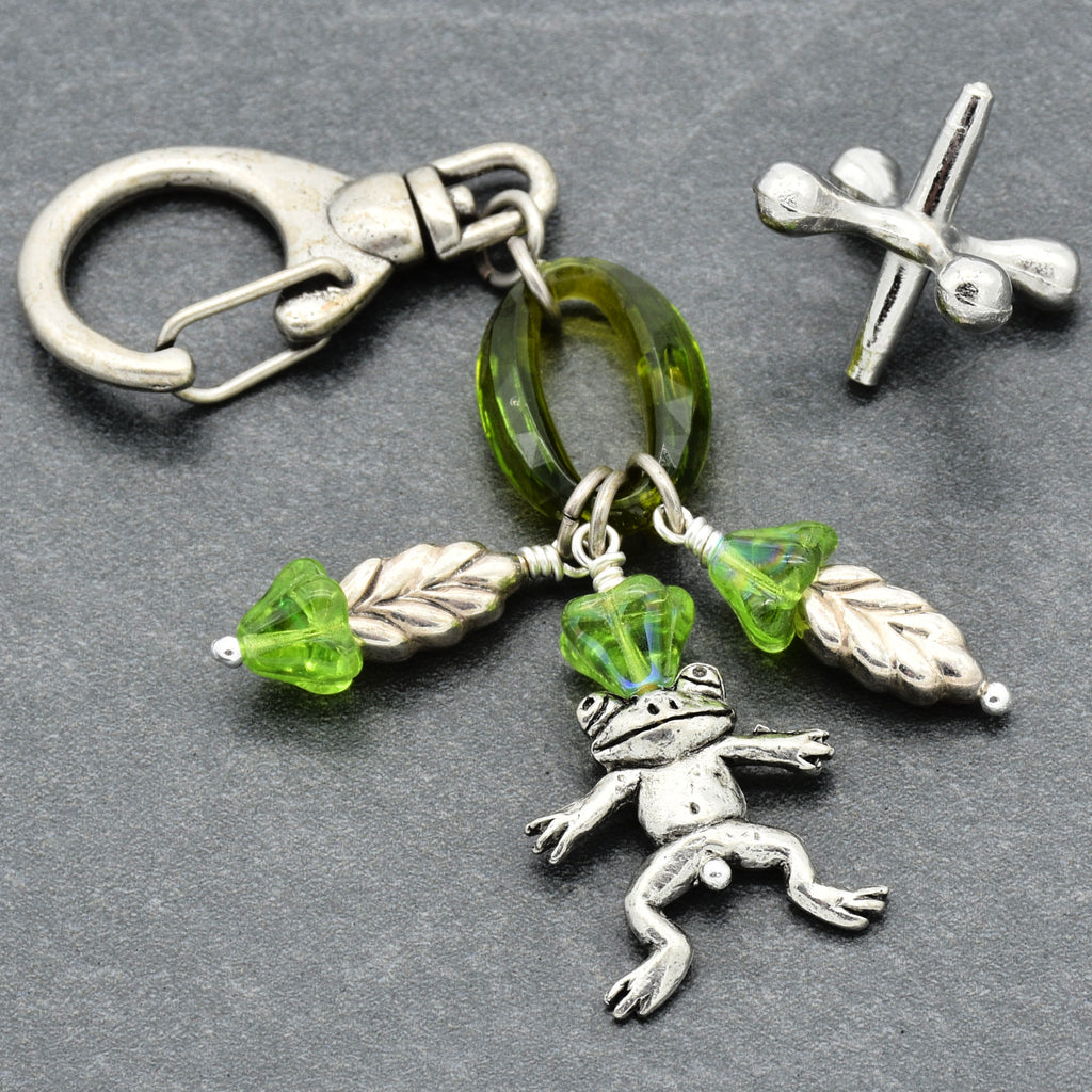 Keychain with frog charm, green beads, and leaf accents on a gray background