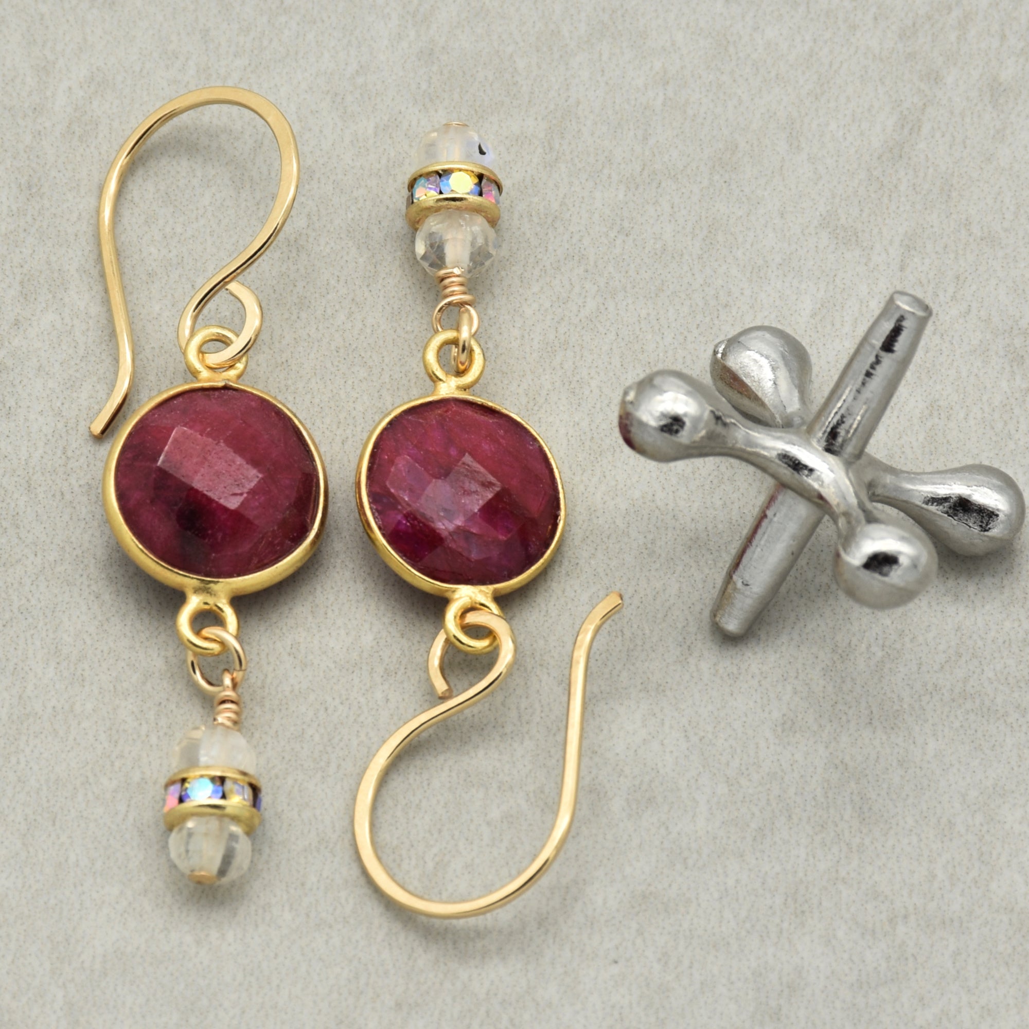 Gold earrings with red gemstones on a gray background