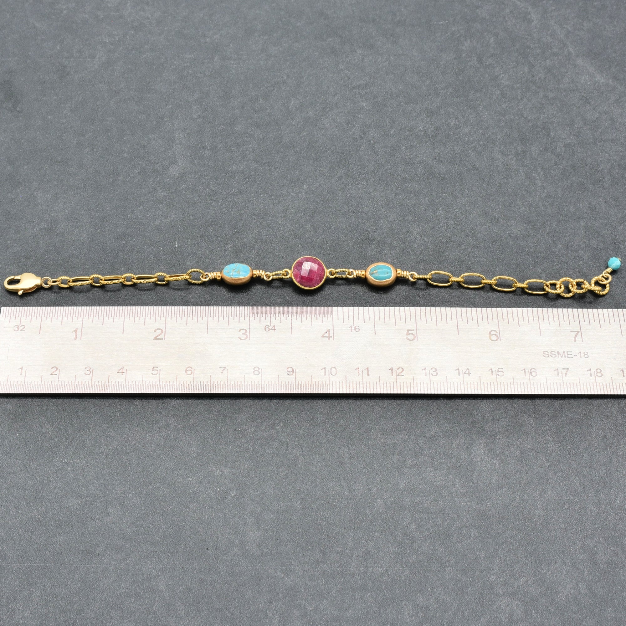 Gold bracelet with colored beads on a gray surface with a ruler for scale - art you can wear by Ruby Acorn