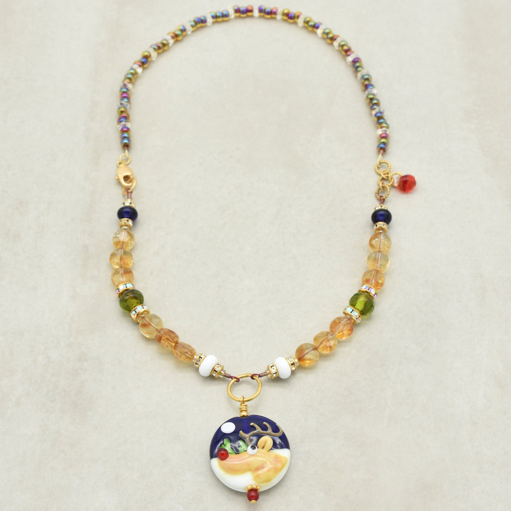 Necklace with colorful beads and a decorative reindeer pendant on a beige background