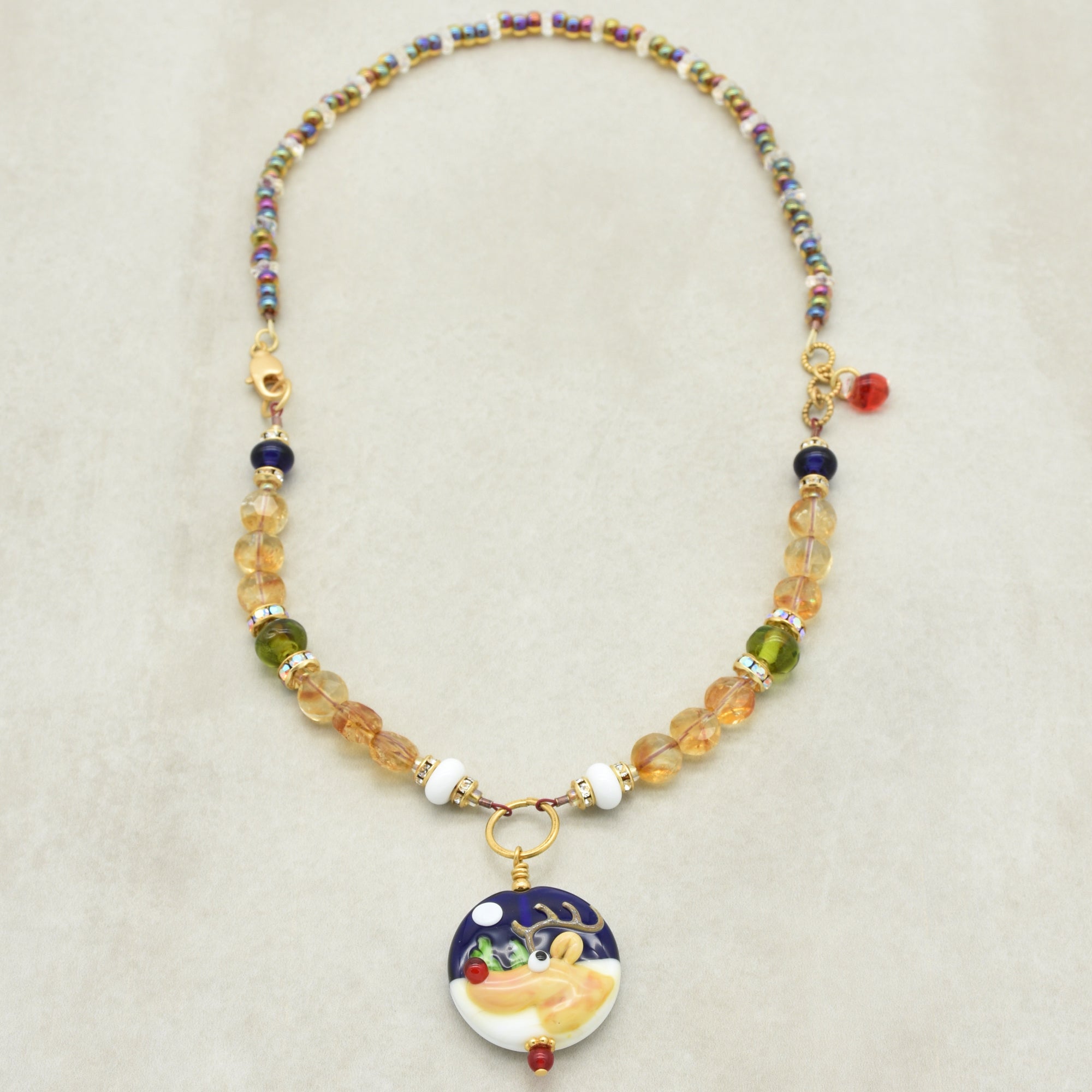 Necklace with colorful beads and a decorative reindeer pendant on a beige background