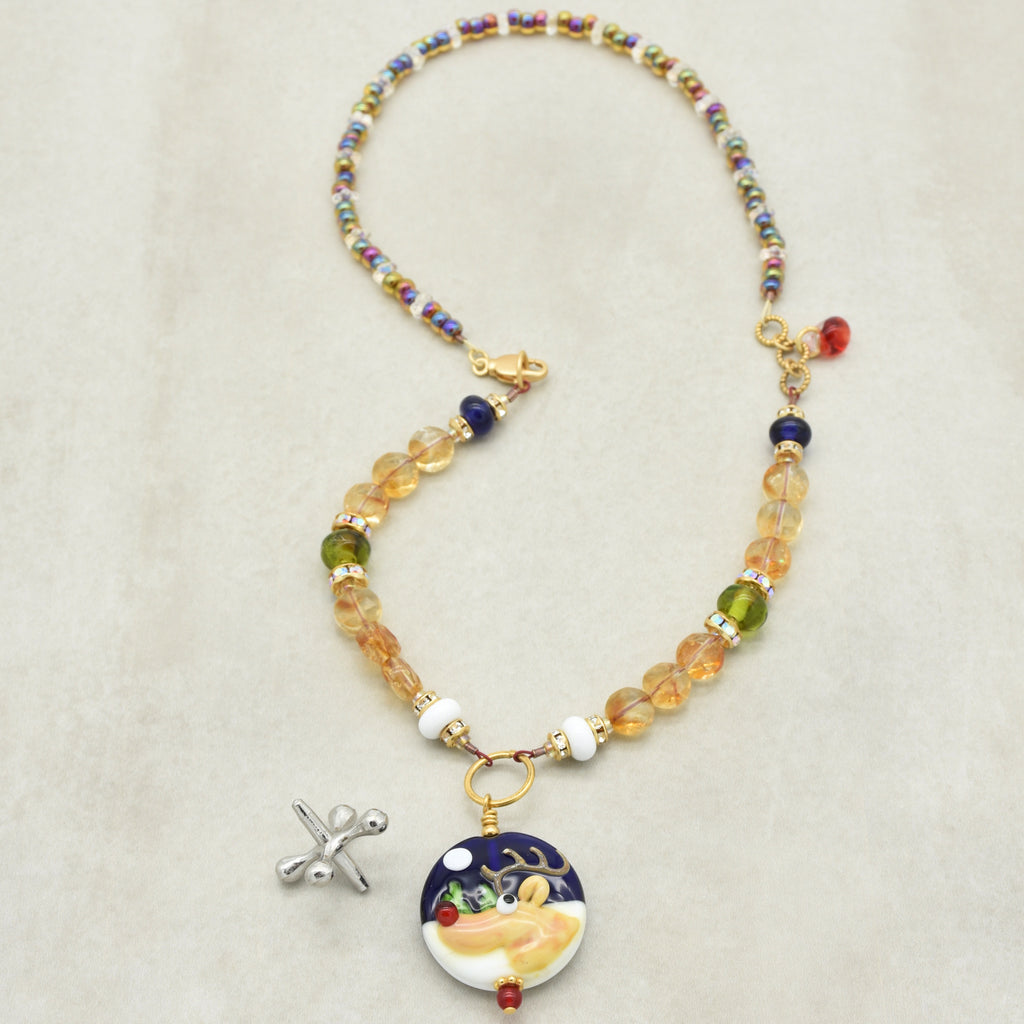 Necklace with colorful beads and a decorative reindeer pendant on a beige background