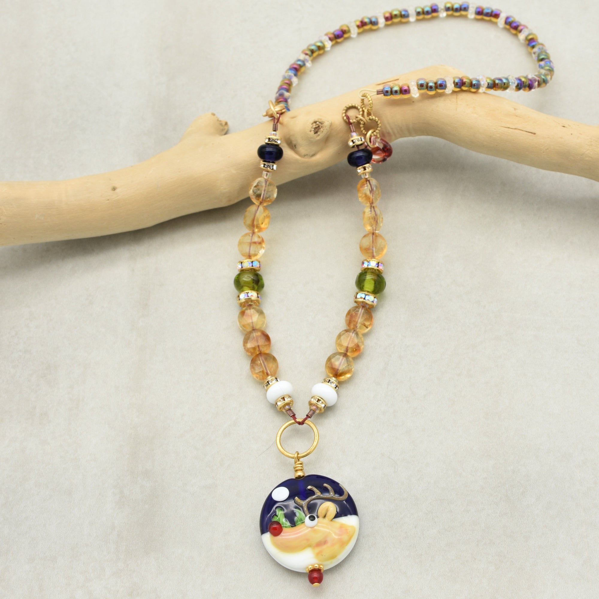 Necklace with colorful beads and a round pendant featuring a reindeer on a beige background