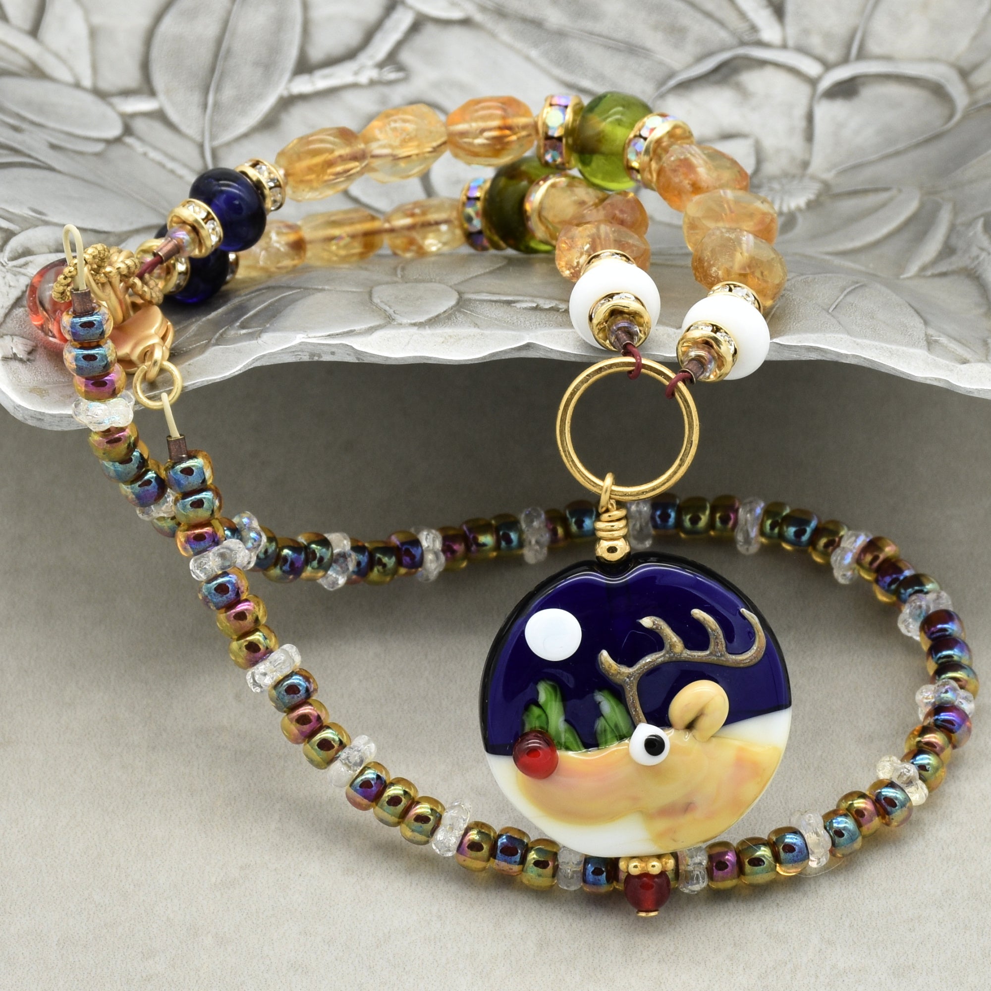 Beaded necklace with a reindeer pendant on a textured surface