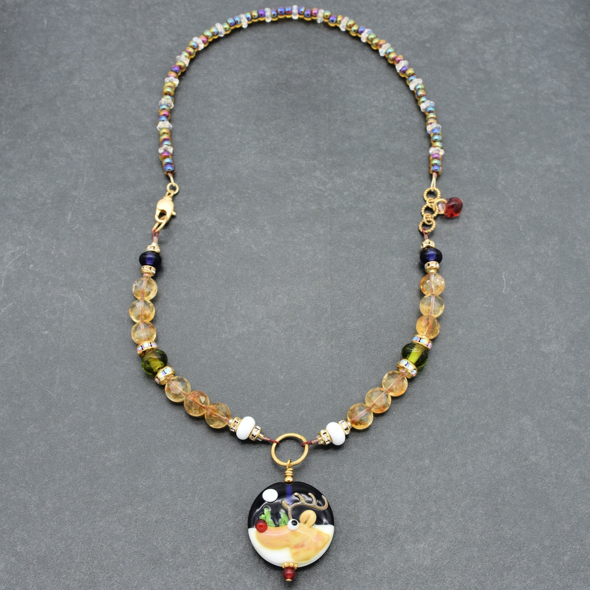 Necklace with colorful beads and a decorative reindeer pendant on a gray background