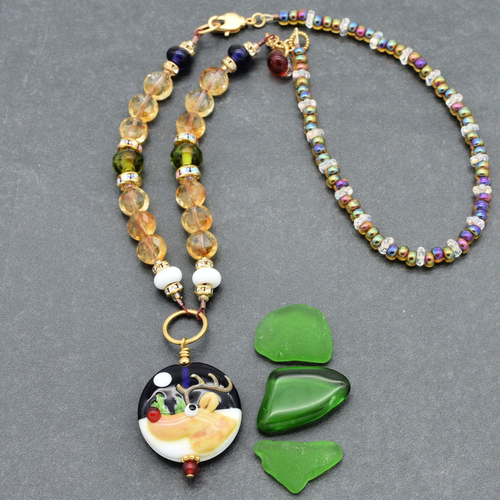 Beaded necklace with a reindeer pendant and festive stones on a gray background